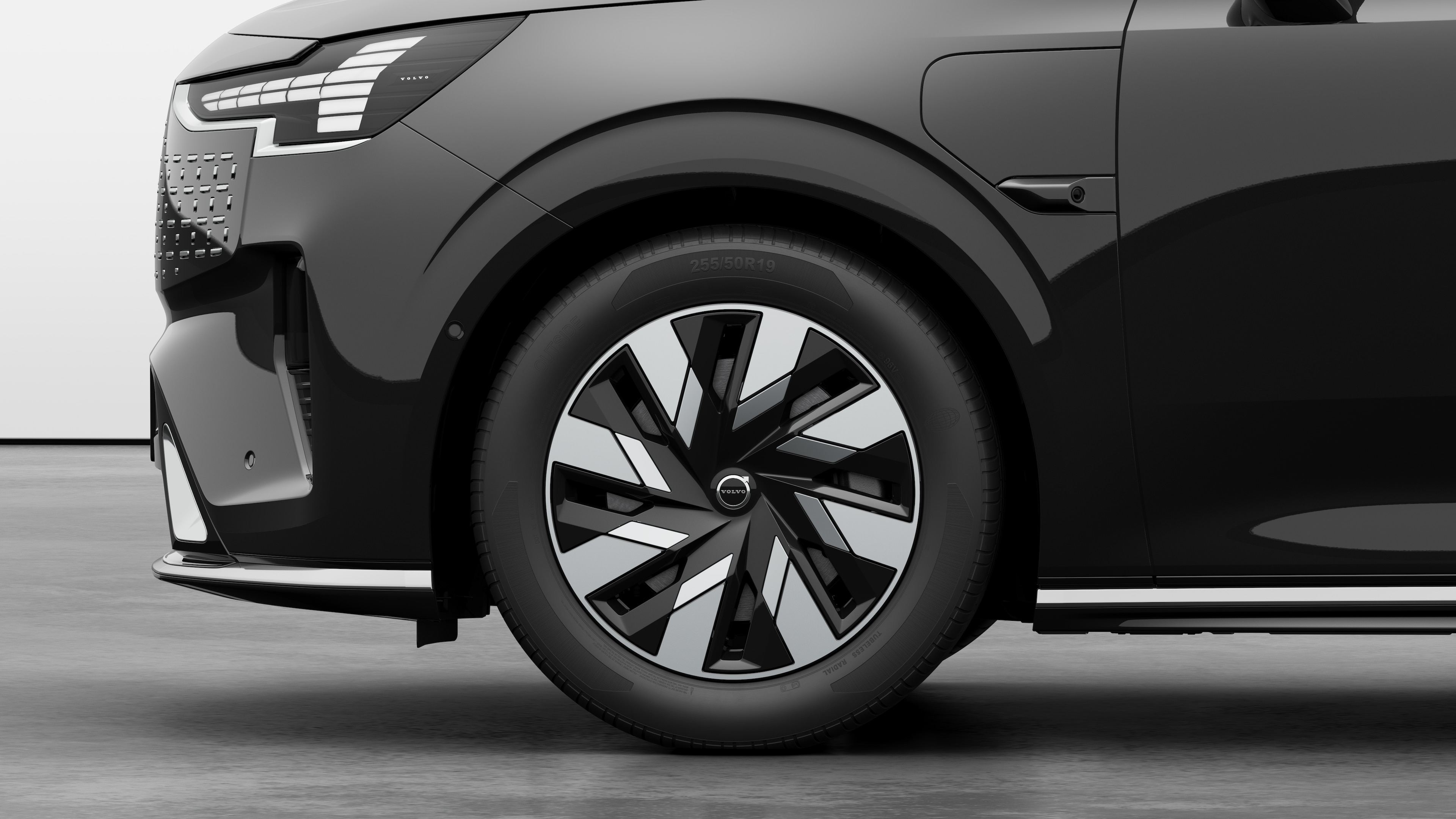 Volvo car exterior side view focusing on the front wheel and fender, set against a plain studio background.