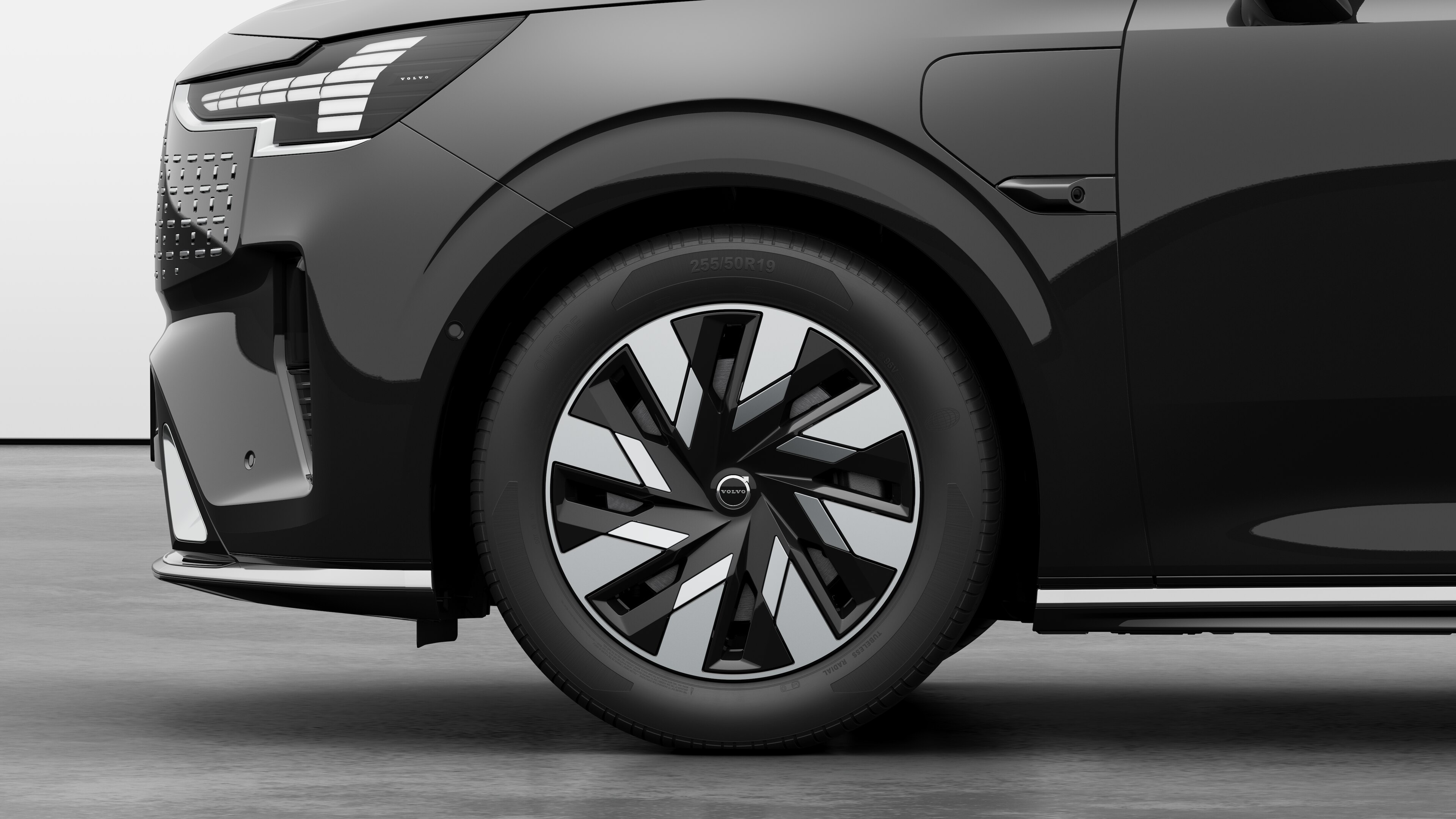 Volvo car exterior side view focusing on the front wheel and fender, set against a plain studio background.