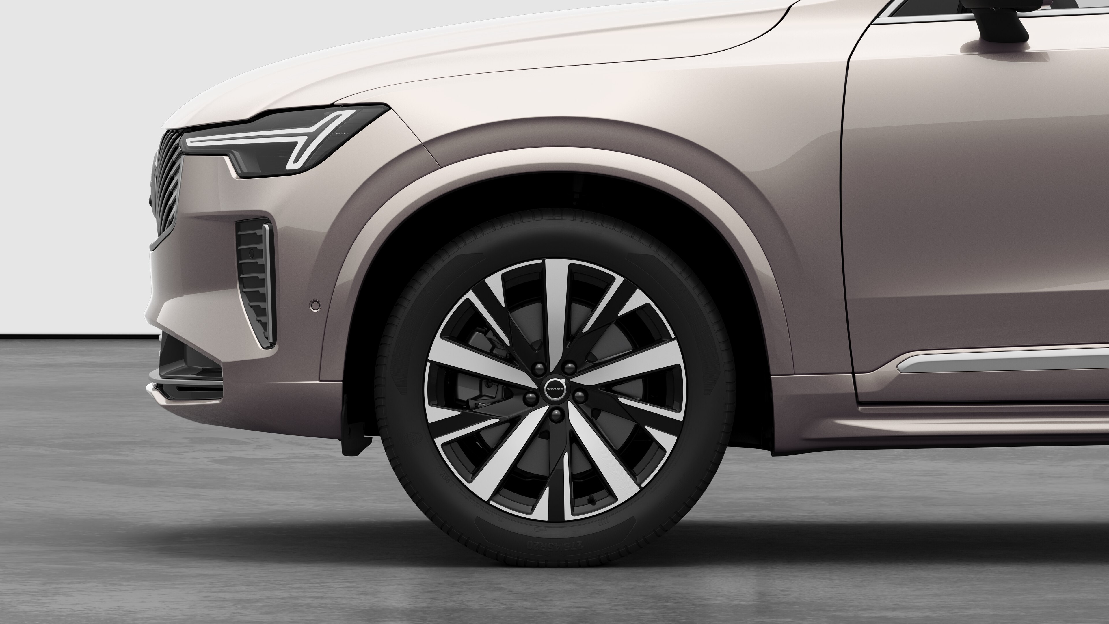 Volvo 汽車外部側視圖聚焦在前輪和擋泥板上，以素色的工作室背景為背景。