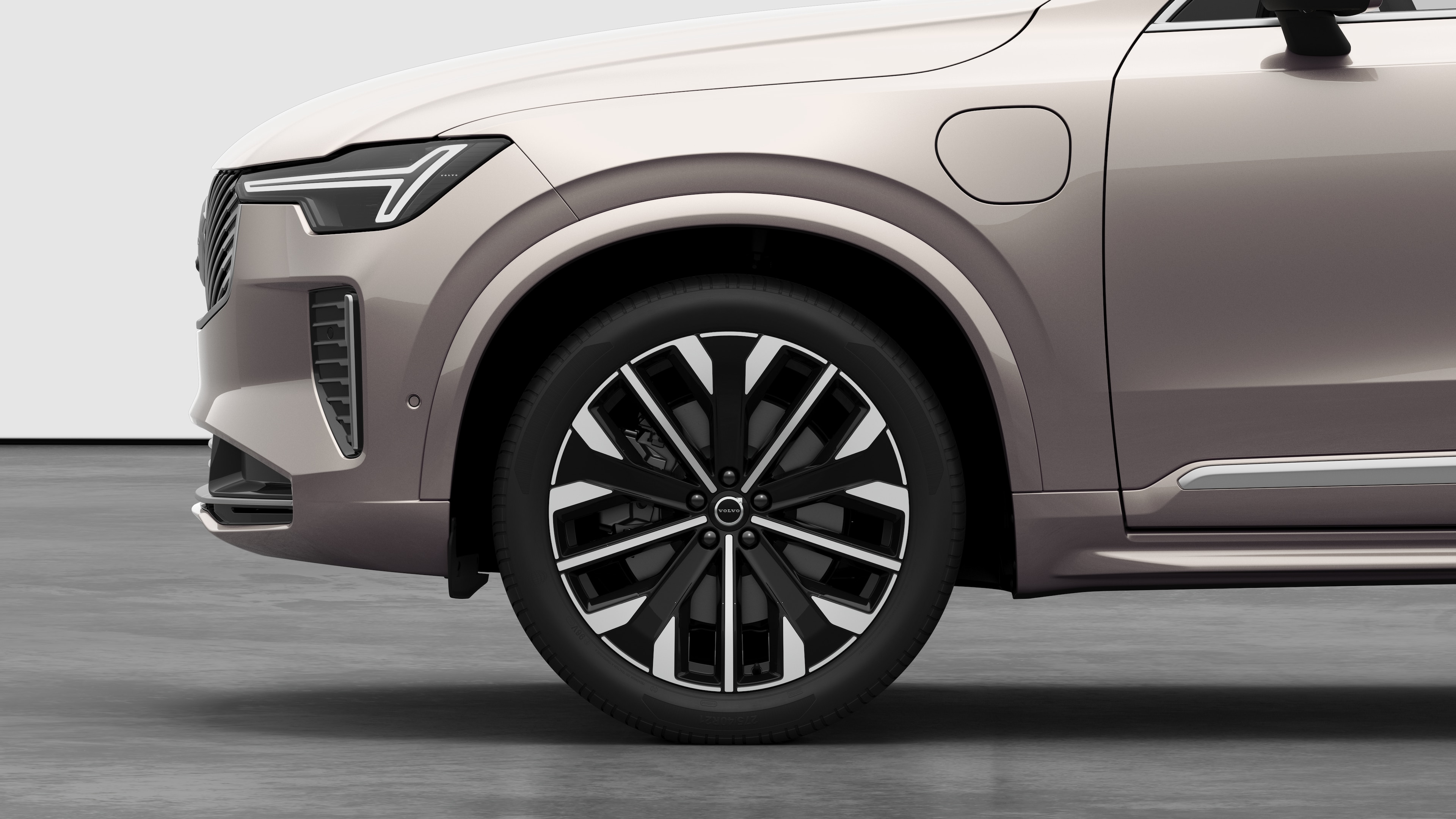 Volvo 汽車外部側視圖聚焦在前輪和擋泥板上，以素色的工作室背景為背景。