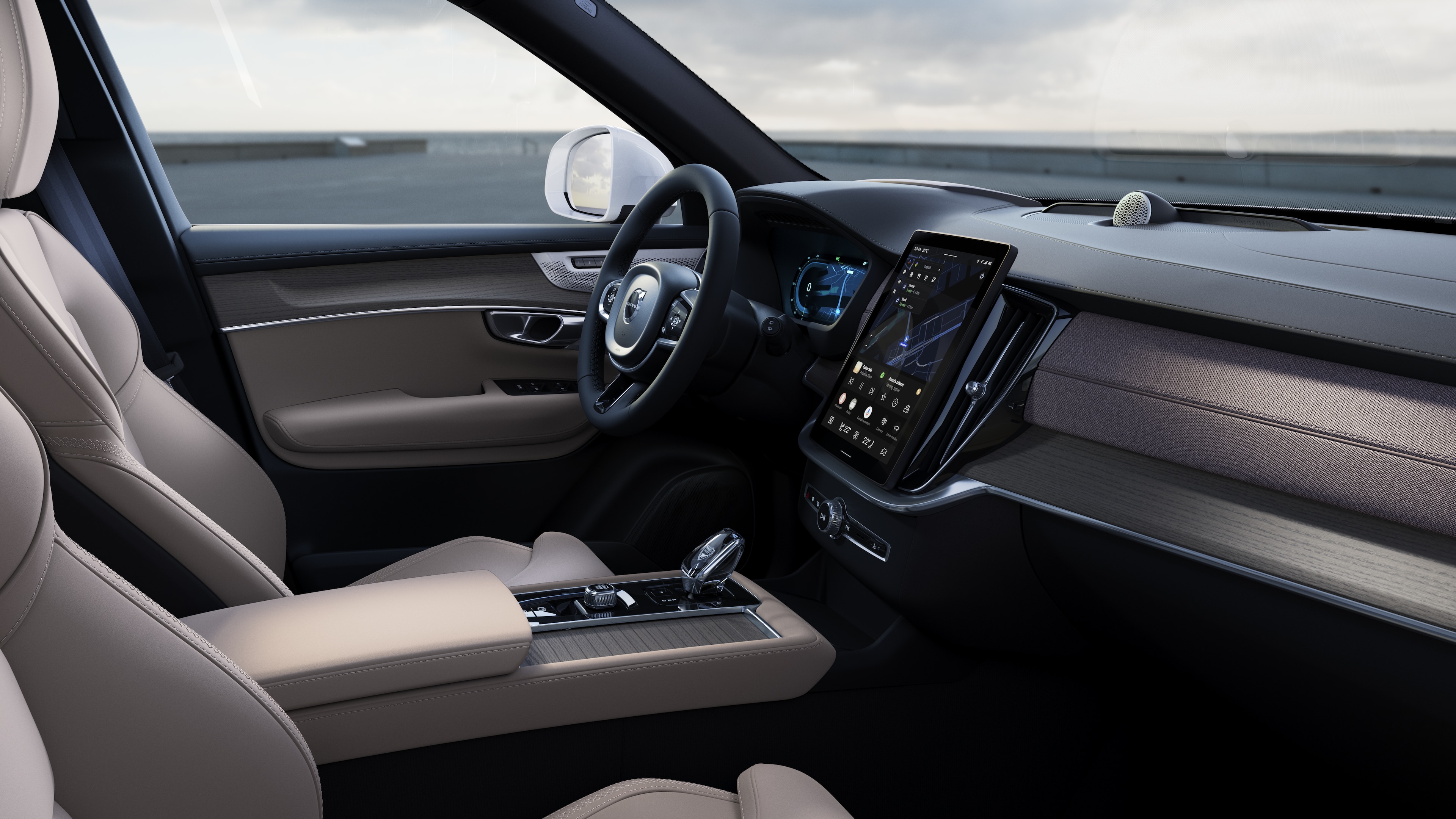 열린 도로 배경에 디지털 디스플레이가 있는 대시보드, 스티어링 휠 및 센터 콘솔을 보여주는 볼보 자동차 내부.