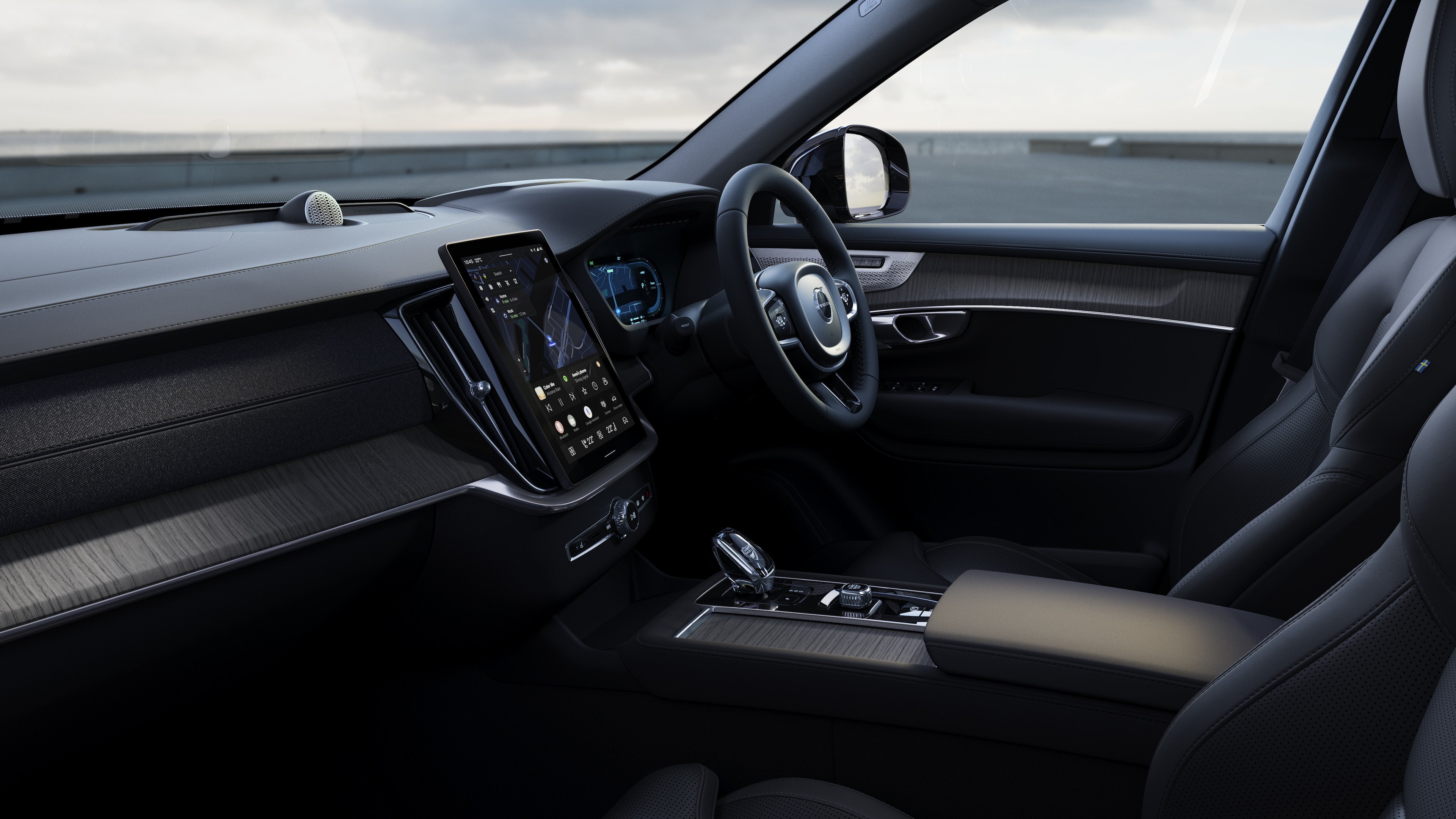 Volvo car interior showing dashboard, steering wheel, and center console with digital display in an open road background.