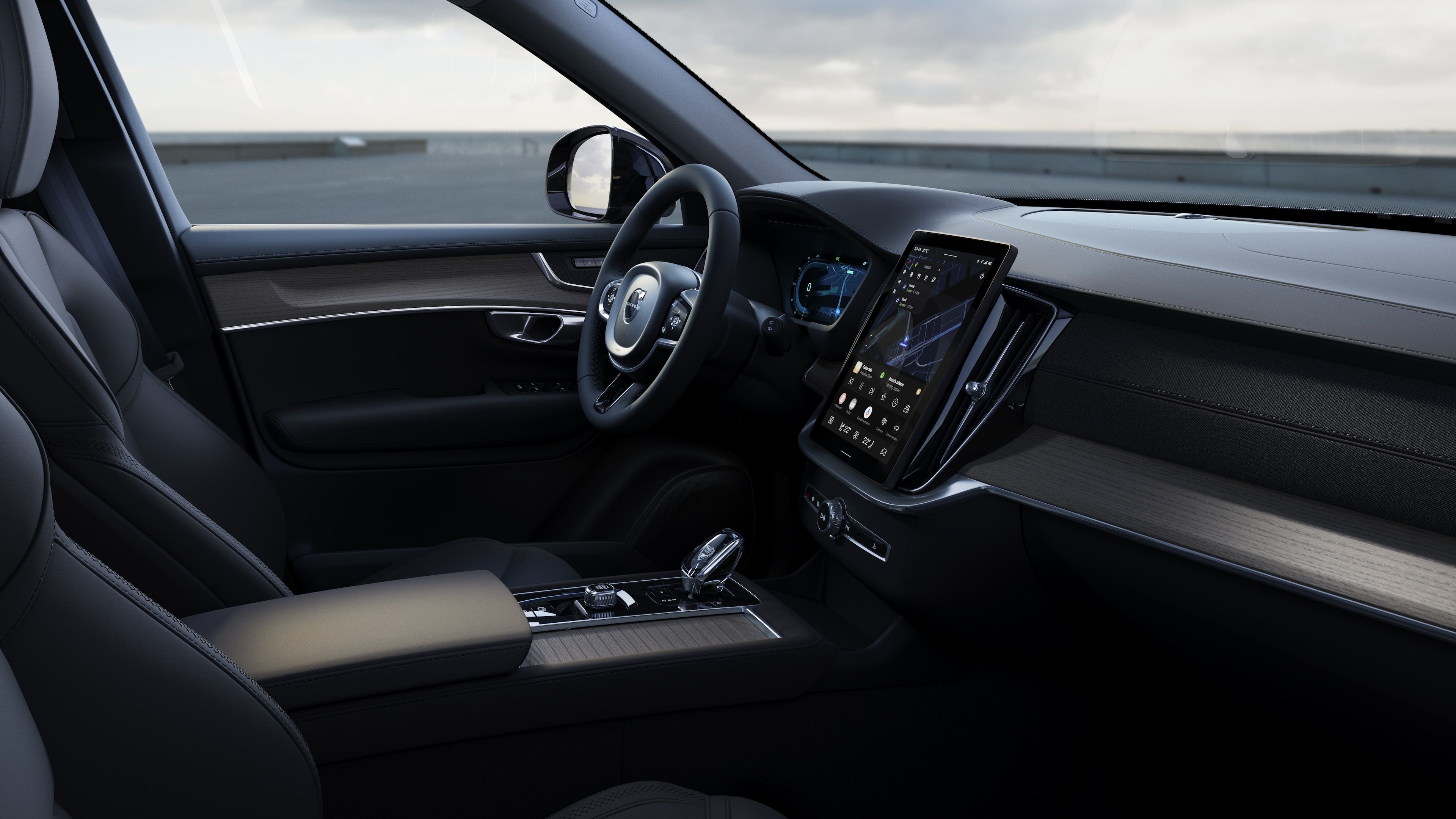 Interior del vehículo Volvo que muestra el salpicadero, el volante y la consola central con pantalla digital en un fondo de carretera abierta.