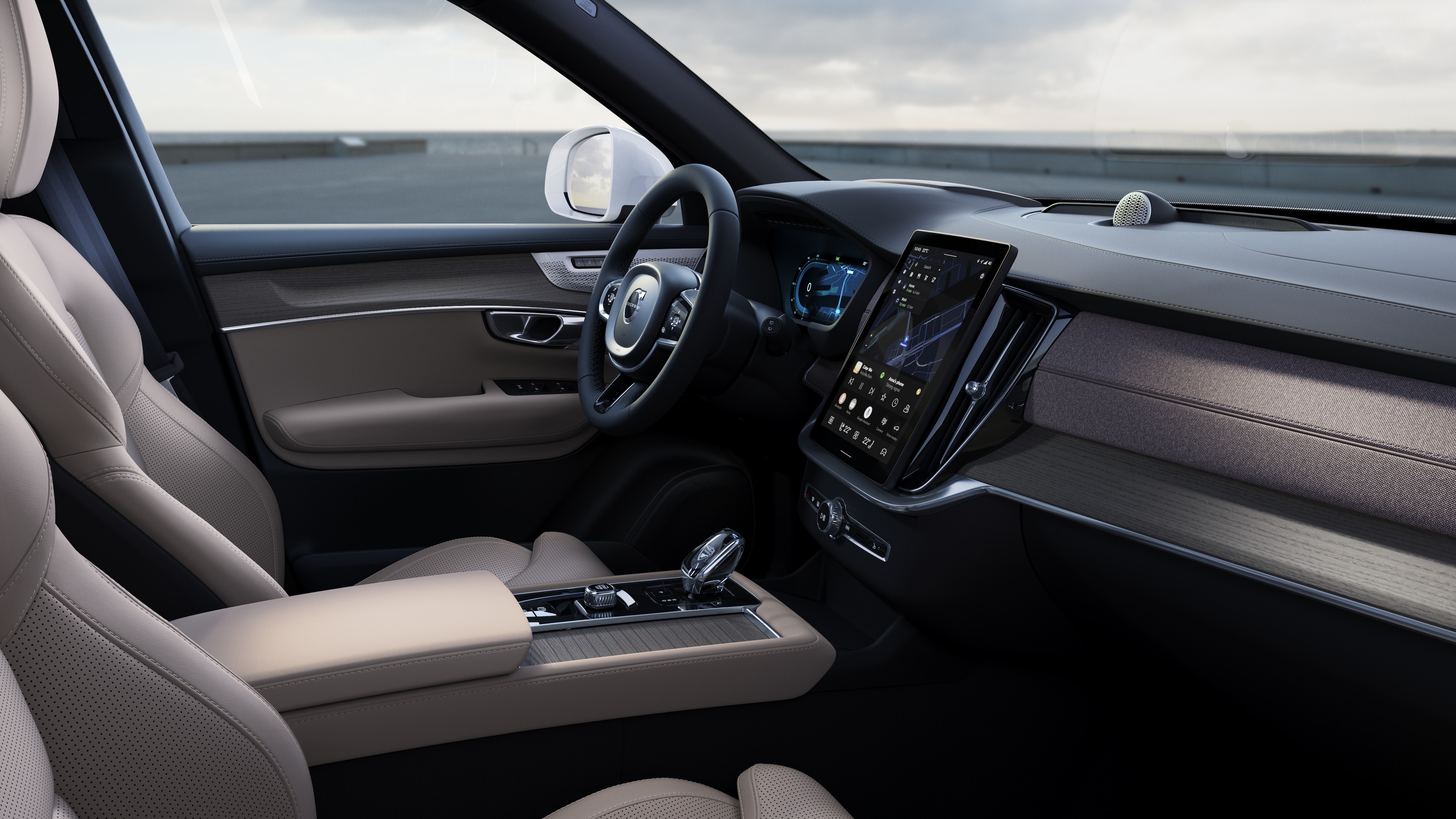 열린 도로 배경에 디지털 디스플레이가 있는 대시보드, 스티어링 휠 및 센터 콘솔을 보여주는 볼보 자동차 내부.