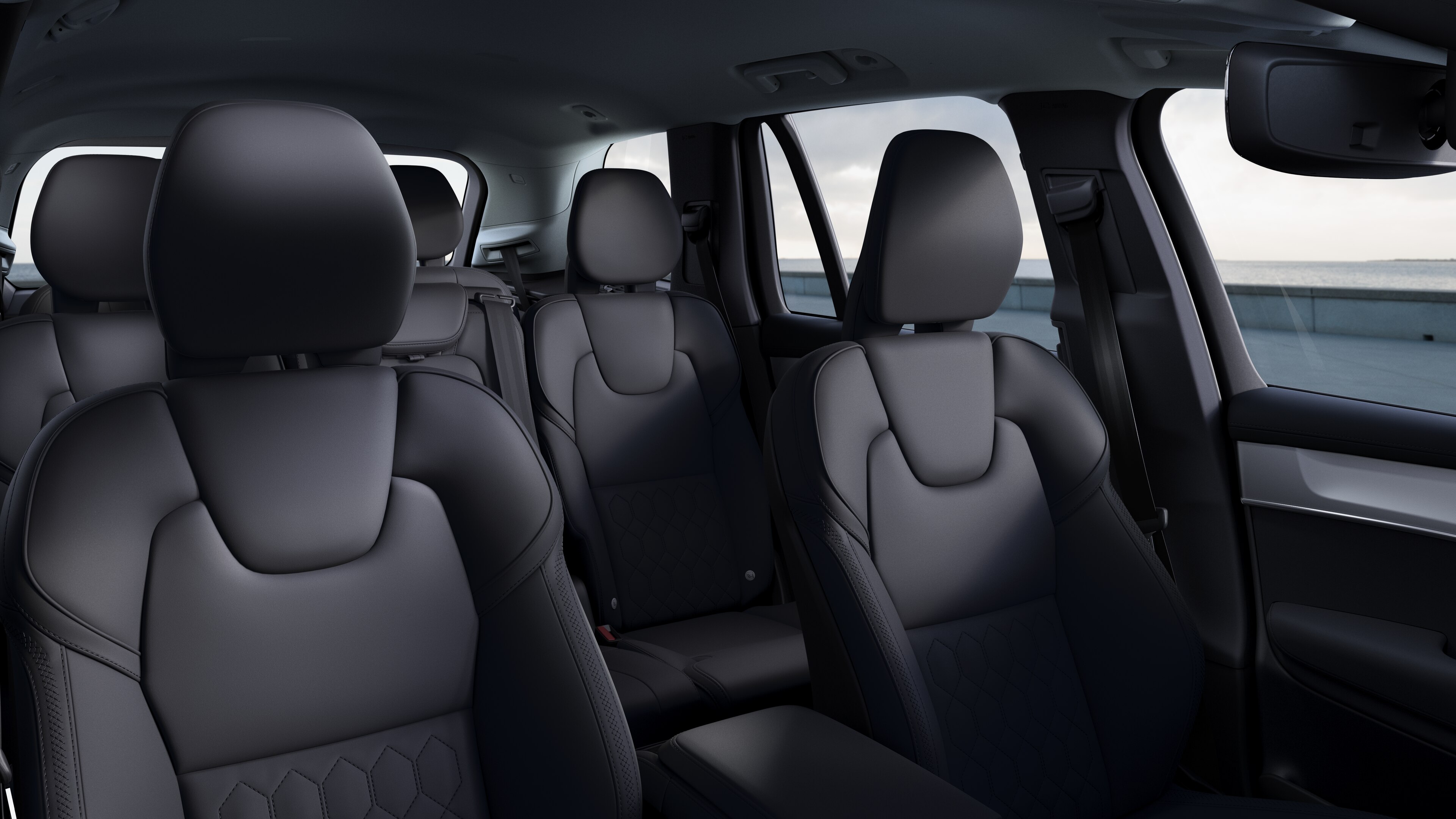 Volvo car interior showing front and rear passenger seats, steering wheel, dashboard, and center console against a plain studio background.