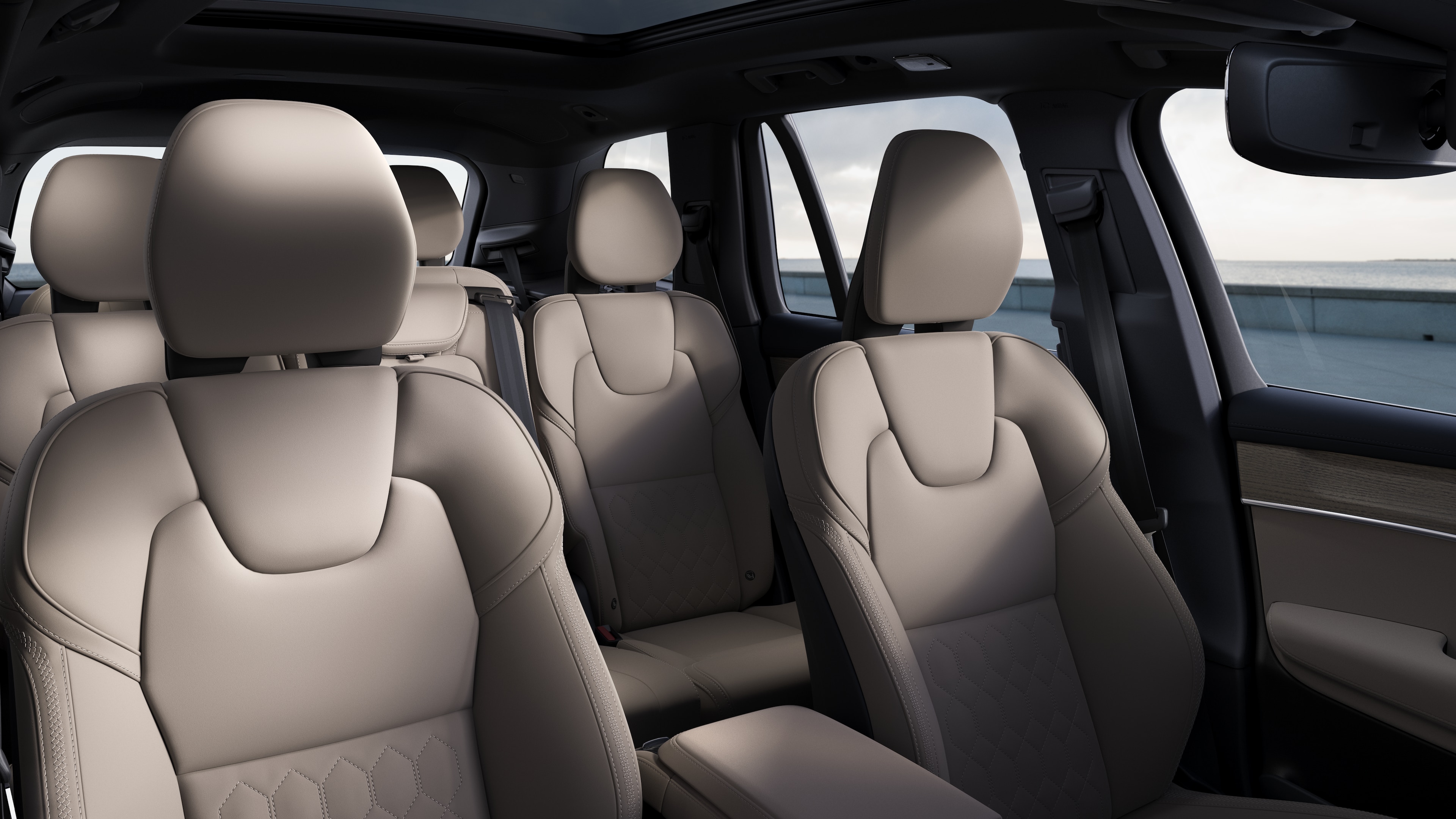 평범한 스튜디오 배경에 앞좌석 및 뒷좌석 조수석, 스티어링 휠, 대시보드 및 센터 콘솔을 보여주는 볼보 자동차 내부.