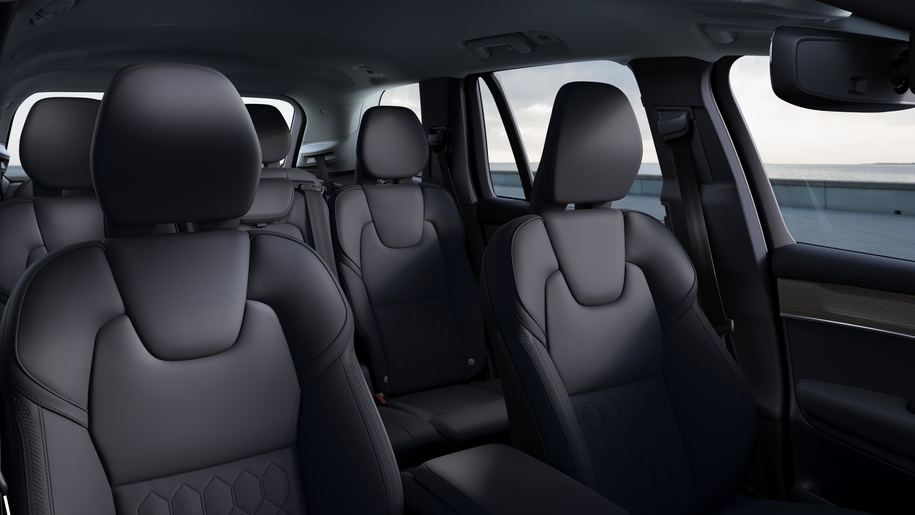 Volvo car interior showing front and rear passenger seats, steering wheel, dashboard, and center console against a plain studio background.