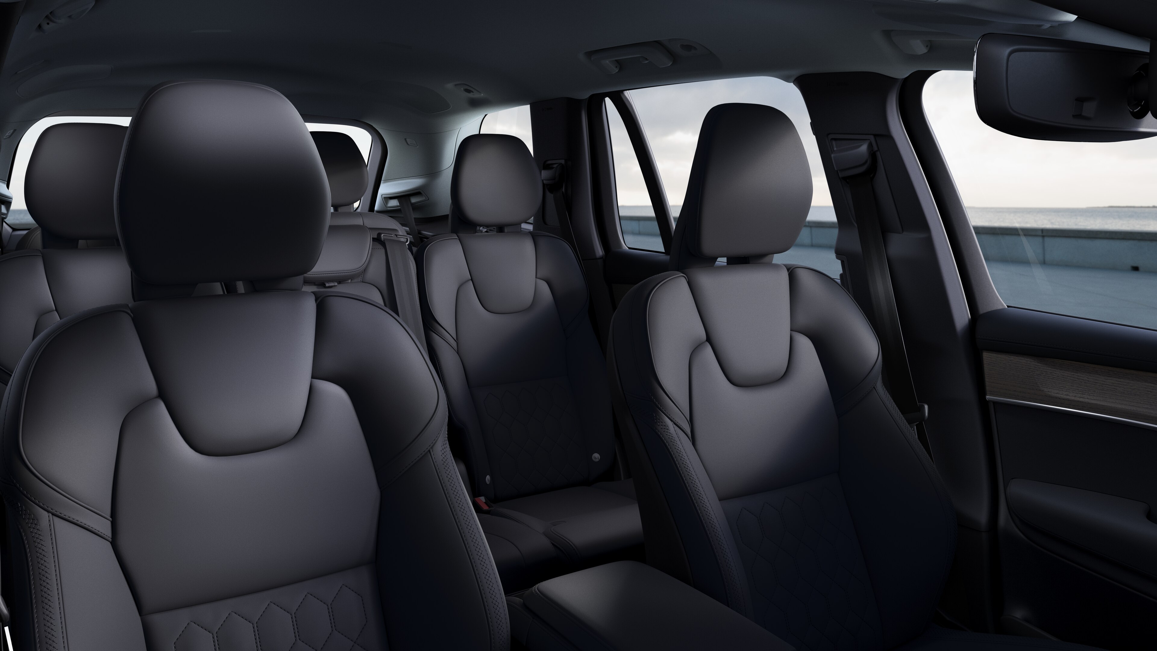 Volvo car interior showing front and rear passenger seats, steering wheel, dashboard, and center console against a plain studio background.