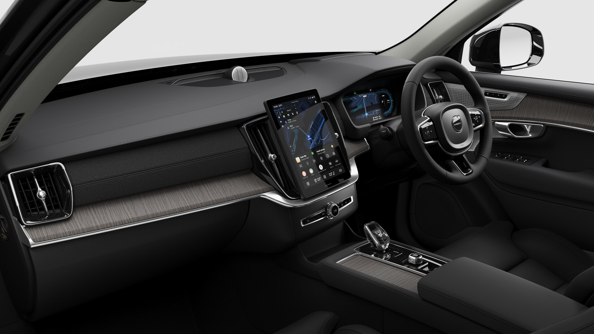 Interior view of a Volvo car showing the dashboard, steering wheel, center console, and digital display screen in a plain studio background.