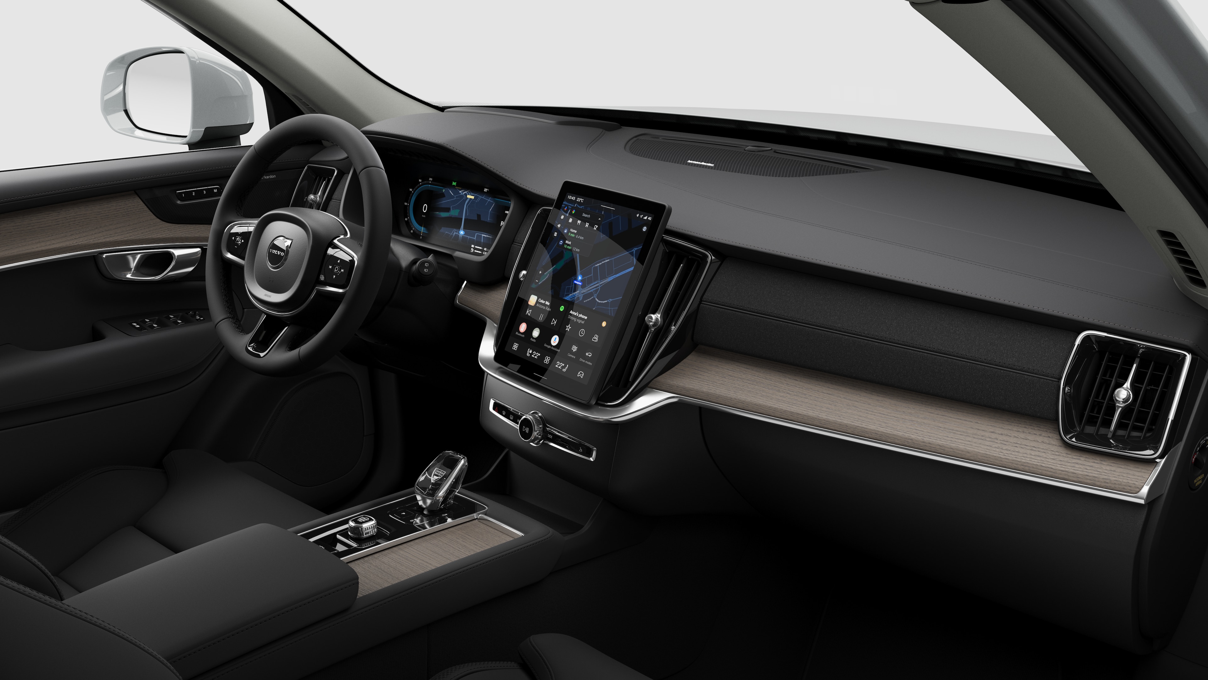 Вид изнутри автомобиля Volvo: приборная панель, руль, центральная консоль и цифровой дисплей на простом студийном фоне.
