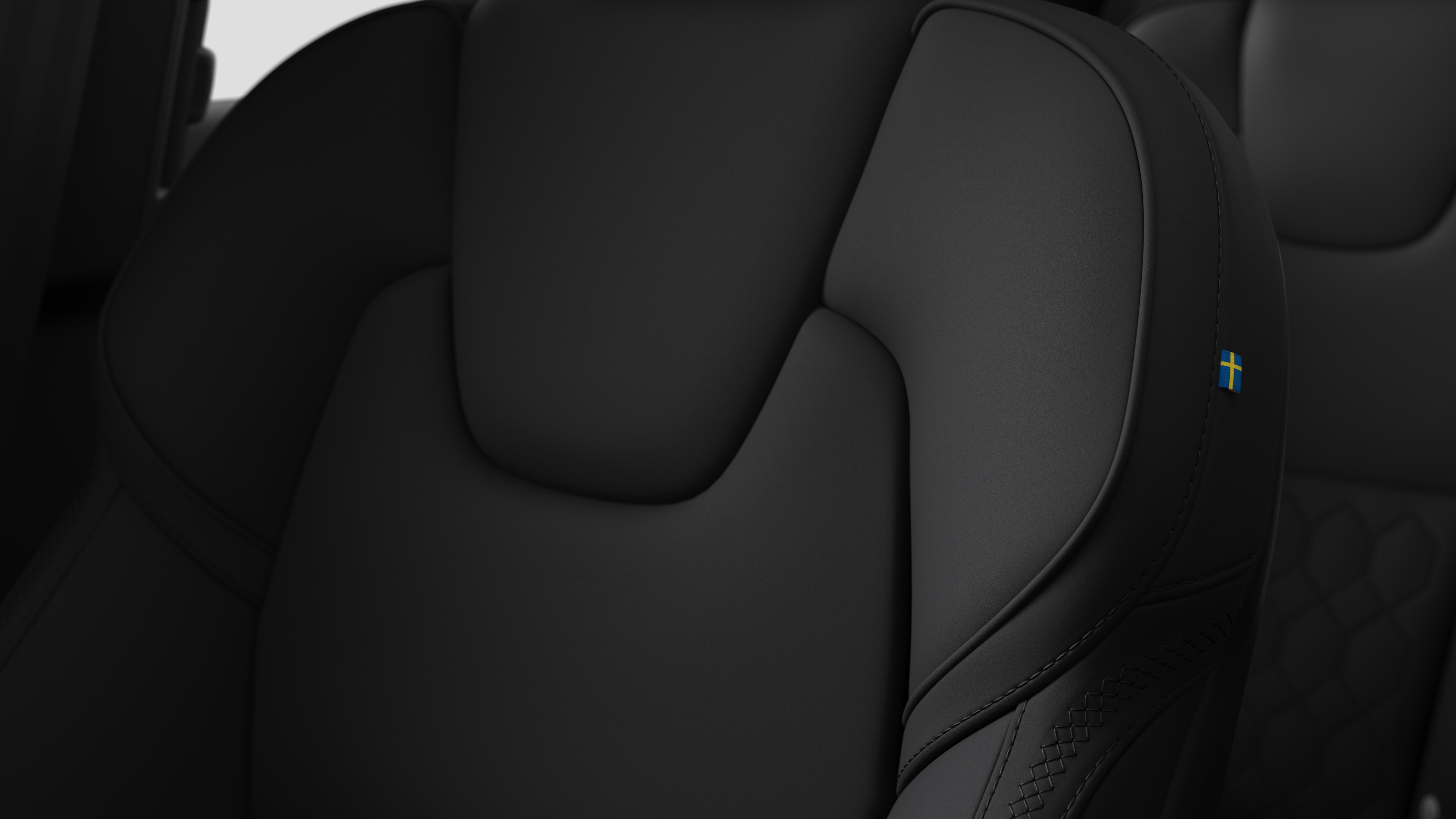 Крупный план деталей салона автомобиля Volvo, на котором видны швы и маленькая бирка с шведским флагом.