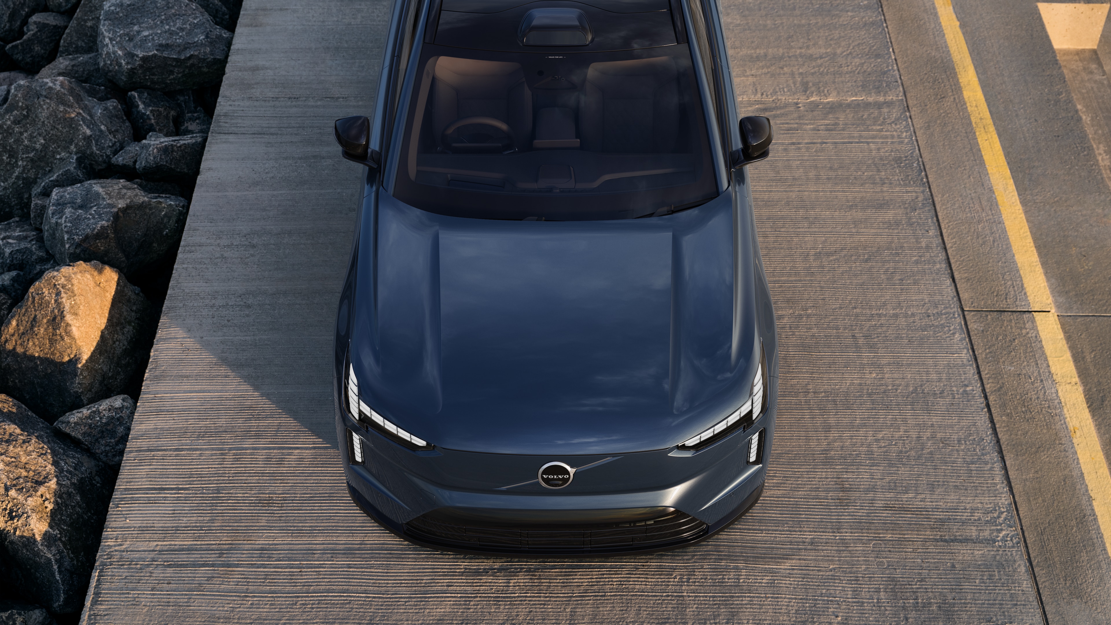 Volvo car exterior in three-quarter view on an urban street background, showing one side, roof, and part of the front.