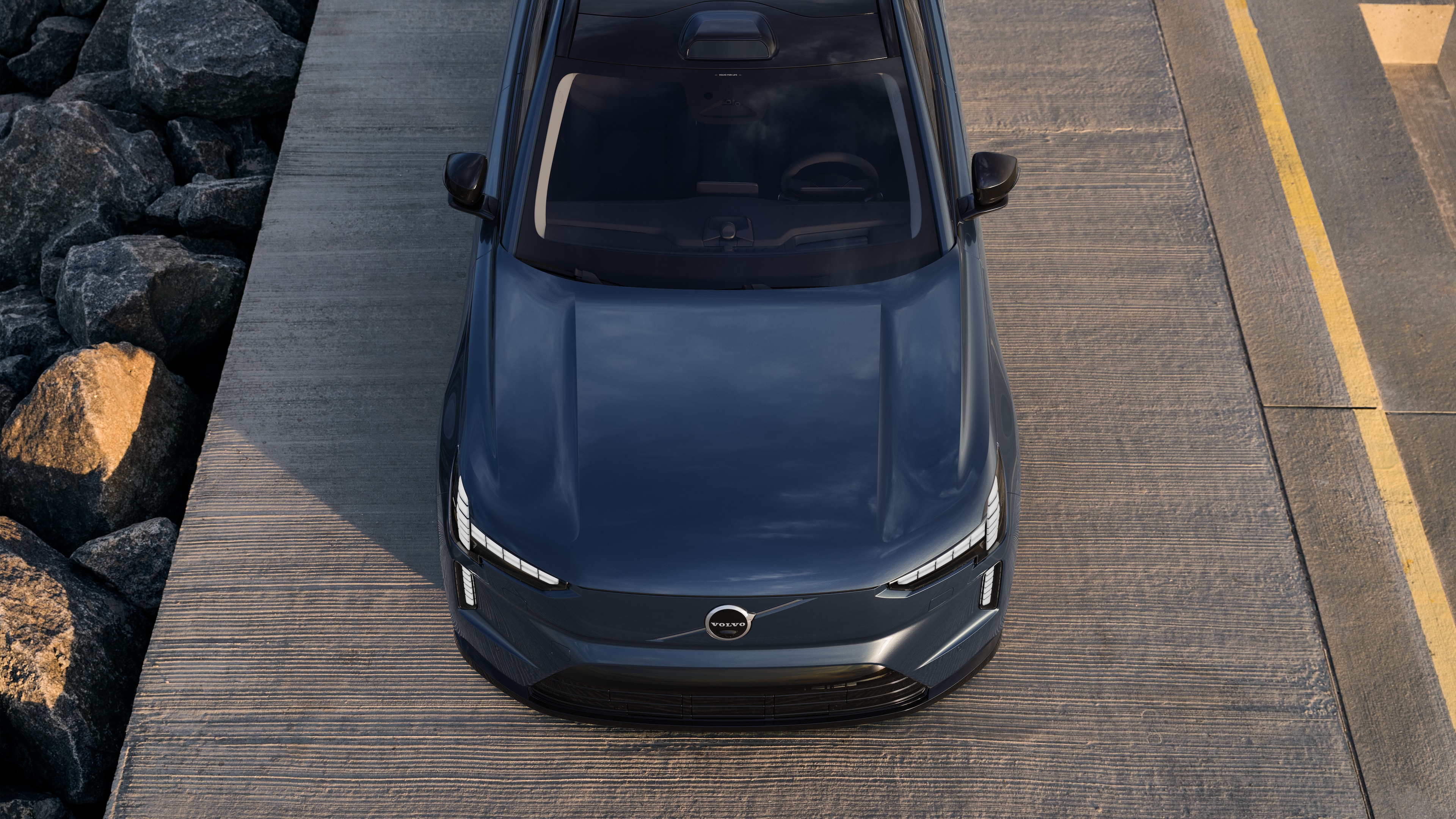 Exterior do carro Volvo em vista de três quartos em um fundo de rua urbana, mostrando um lado, teto e parte da frente.