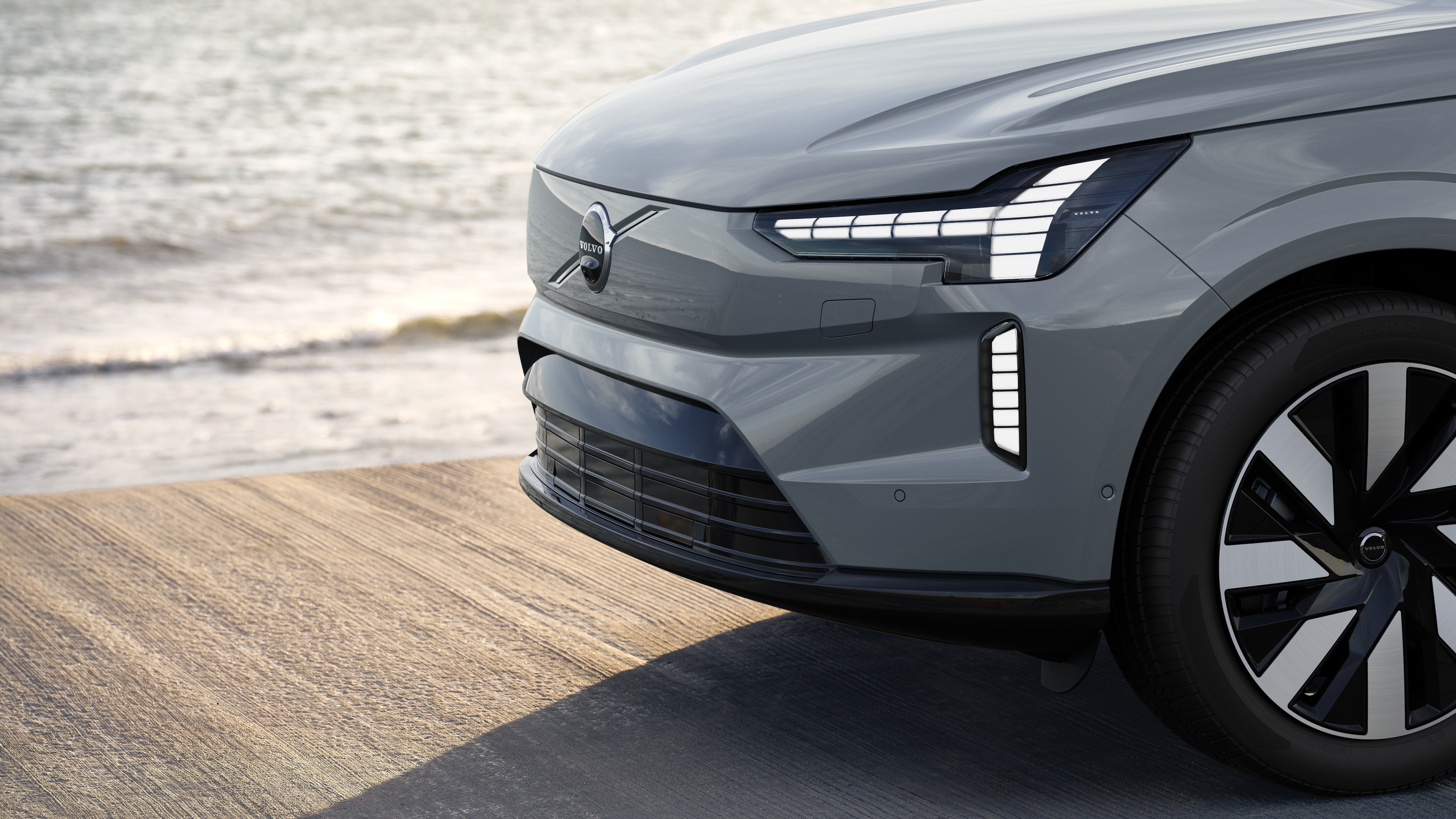 Volvo-bíll að utan í þriggja fjórðu hluta myndar við iðnaðar steinsteyptan vegg í bakgrunni.