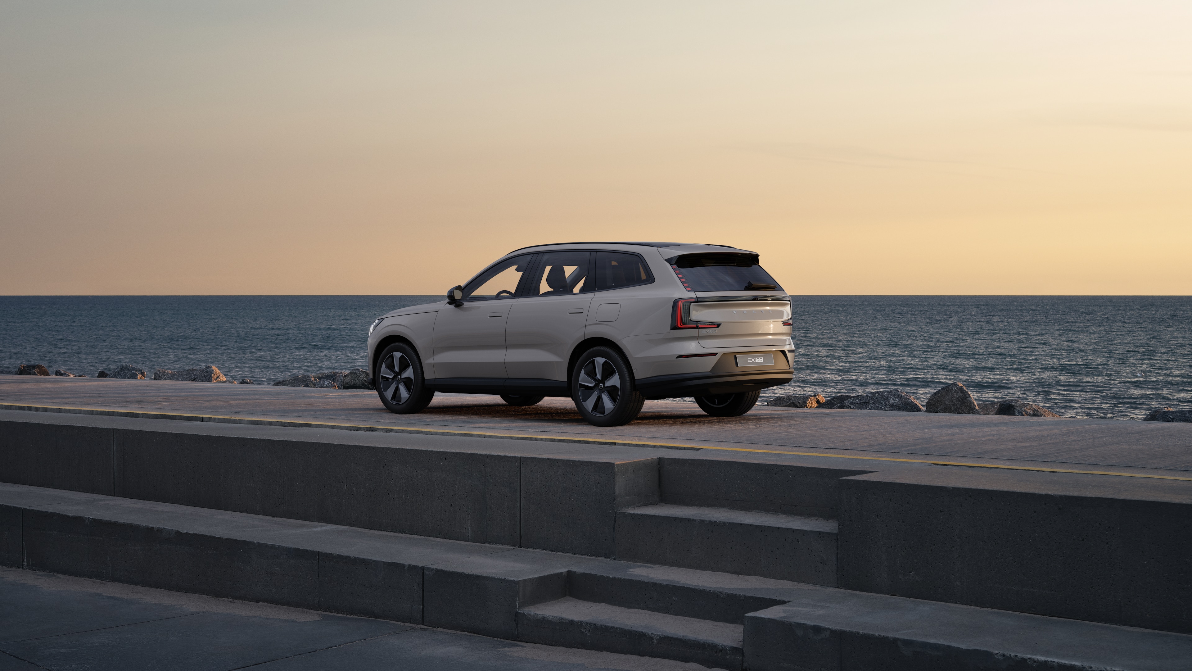 Vue arrière d’une Volvo de trois quarts, garée contre un mur de béton sur un fond de rue urbaine.
