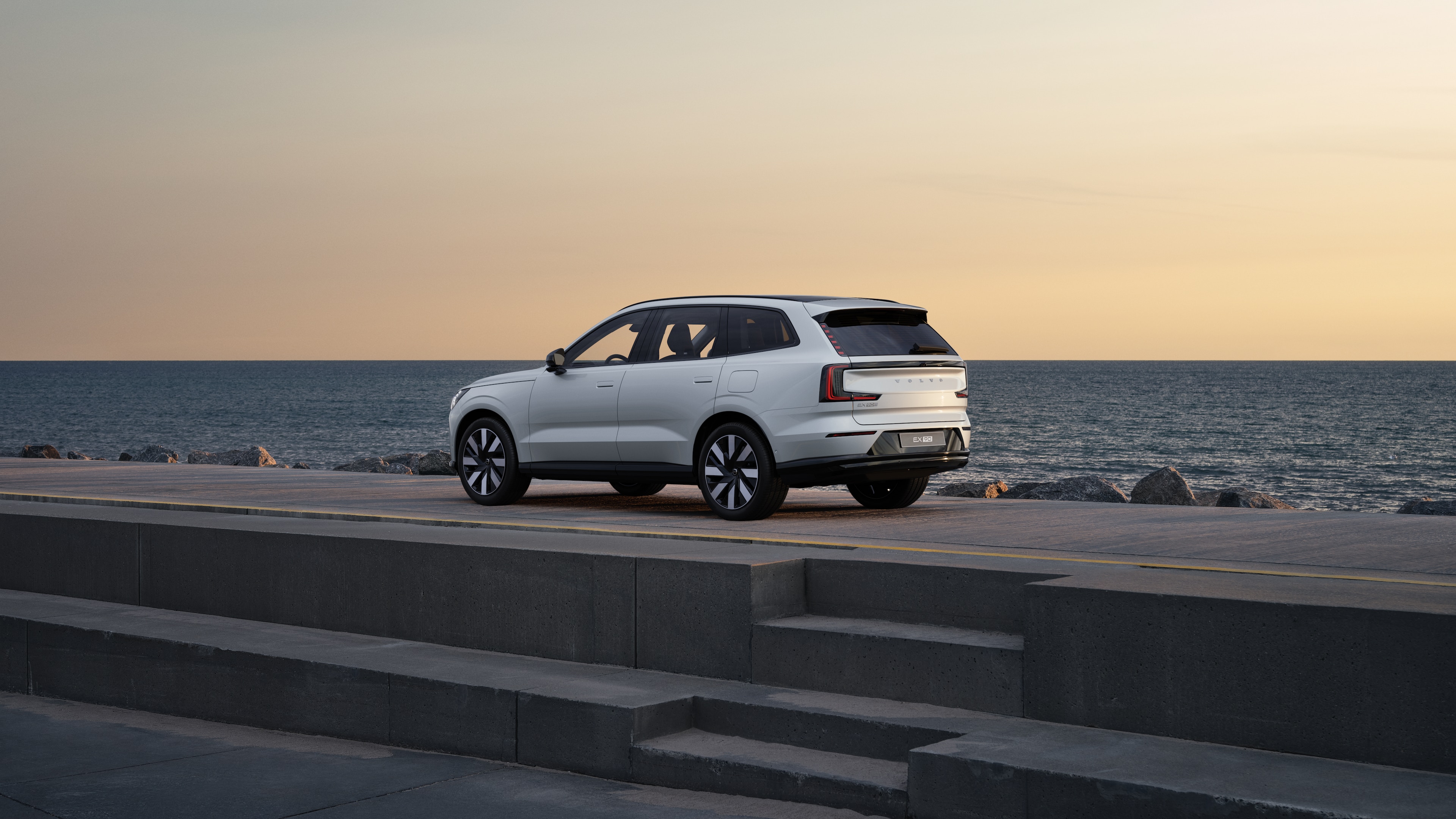 Αυτοκίνητο Volvo σε πίσω όψη τριών τετάρτων, σταθμευμένο σε τσιμεντένιο τοίχο σε αστικό φόντο.