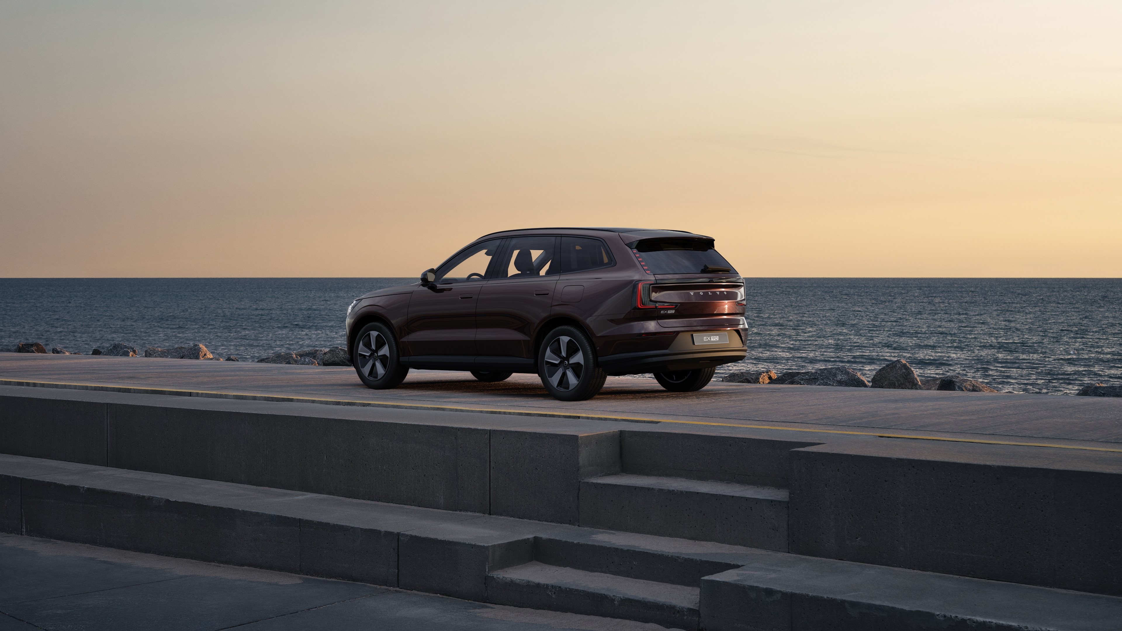 Samochód Volvo w widoku z tyłu w trzech czwartych zaparkowany przy murze na tle miejskiej ulicy