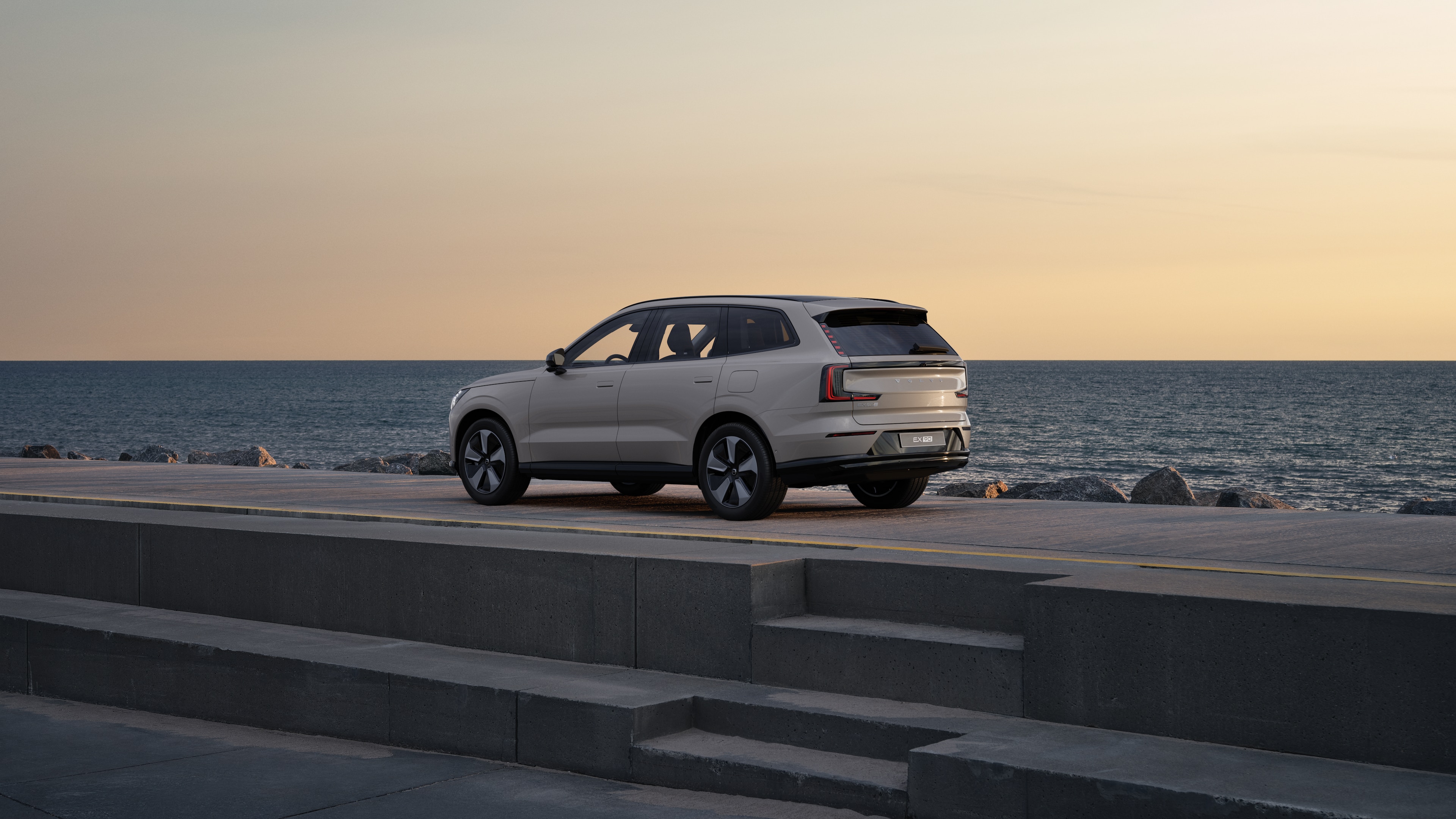 Trekvart visning av Volvo bak parkert mot en betongvegg i en urban gatebakgrunn.