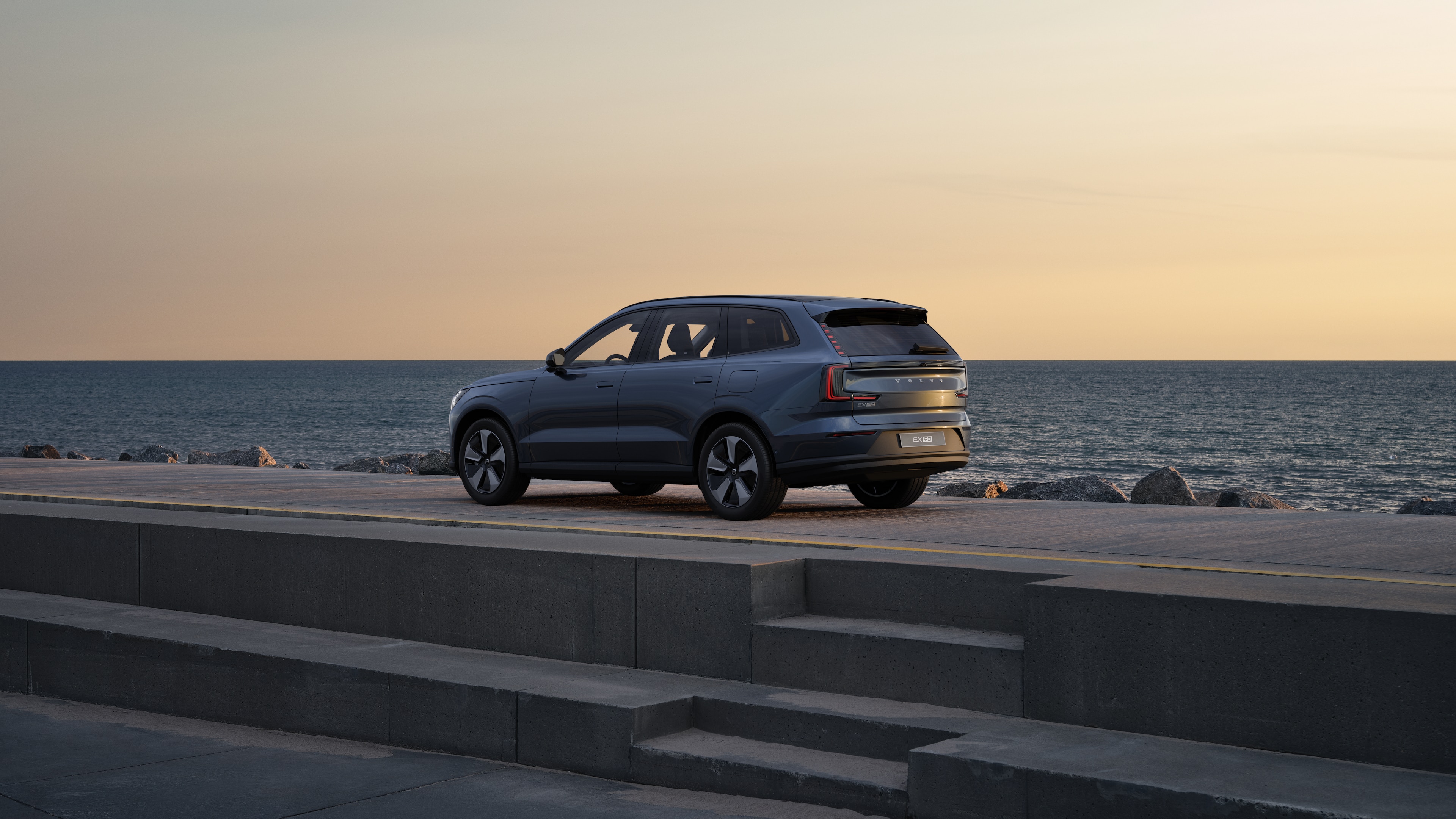 Samochód Volvo w widoku z tyłu w trzech czwartych zaparkowany przy murze na tle miejskiej ulicy