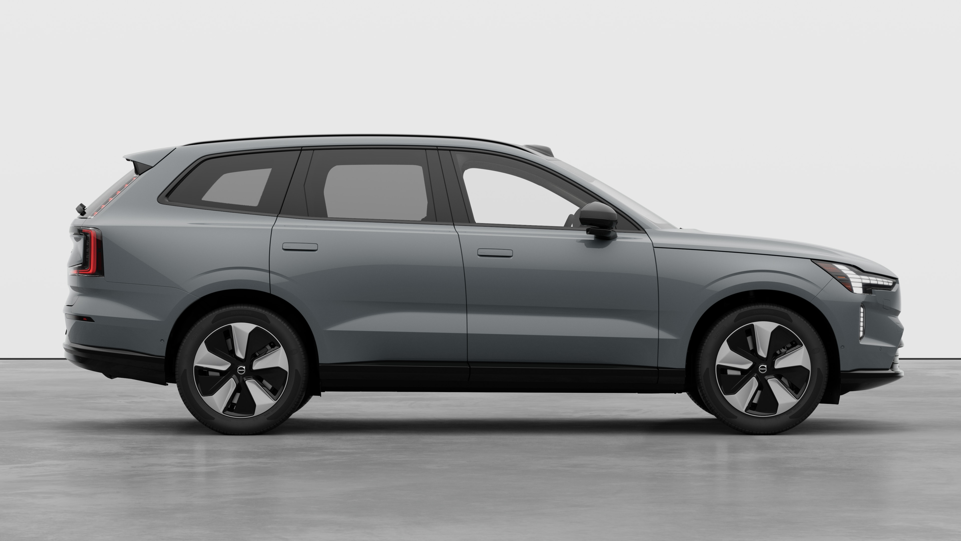 Volvo car side view on plain studio background displaying closed doors and visible wheel design.
