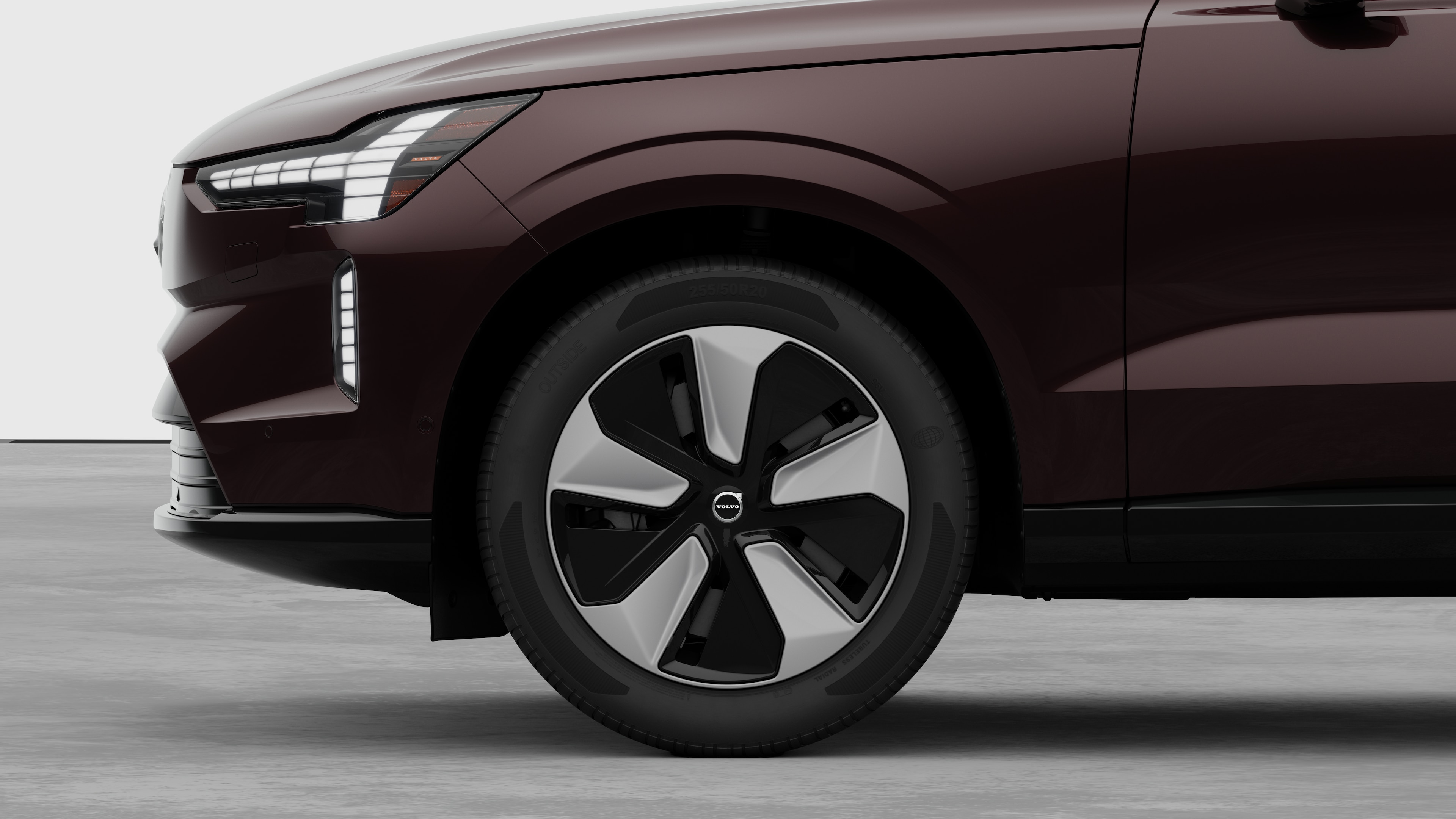 Vue latérale de l’extérieur d’une voiture Volvo, avec l’accent mis sur la roue avant et l’aile, sur un fond de studio uni.