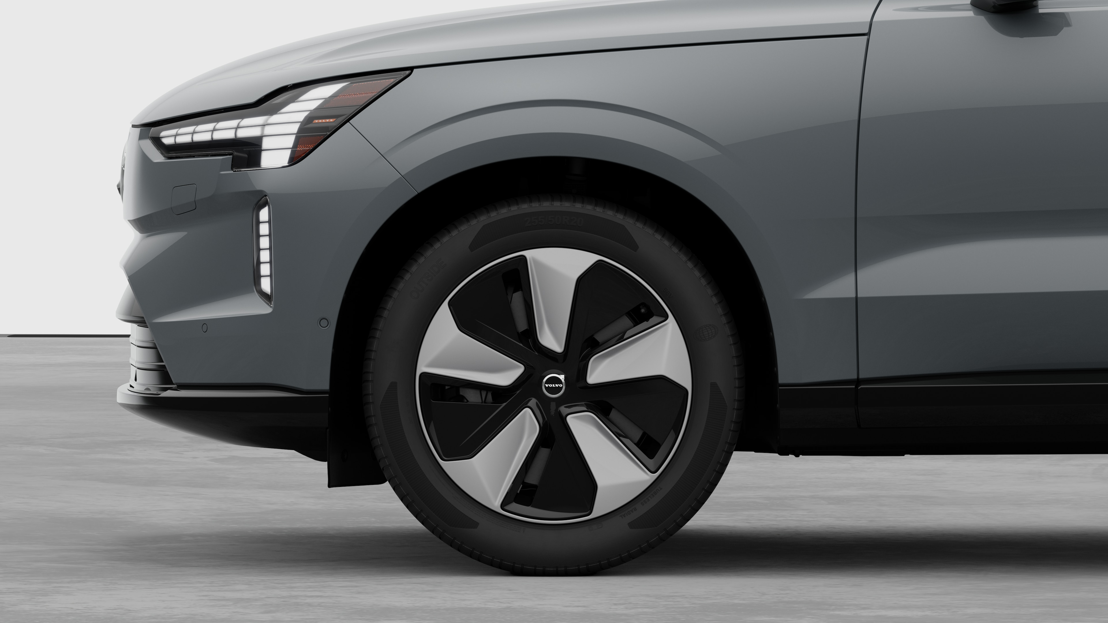 Volvo car exterior side view focusing on the front wheel and fender, set against a plain studio background.