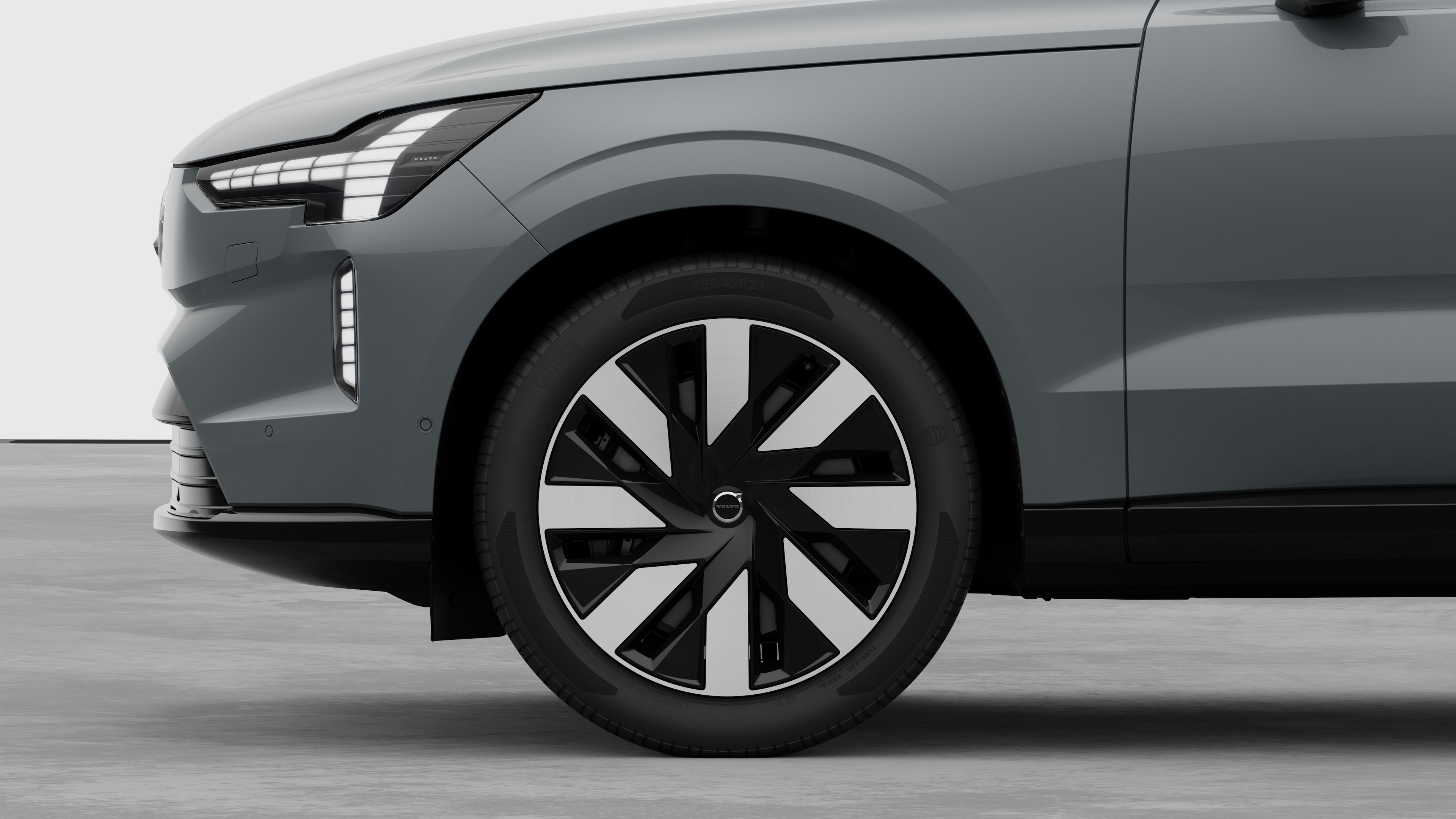 Το εξωτερικό τμήμα ενός αυτοκινήτου Volvo εστιάζει στον μπροστινό τροχό και το φτερό, με φόντο ένα απλό στούντιο.