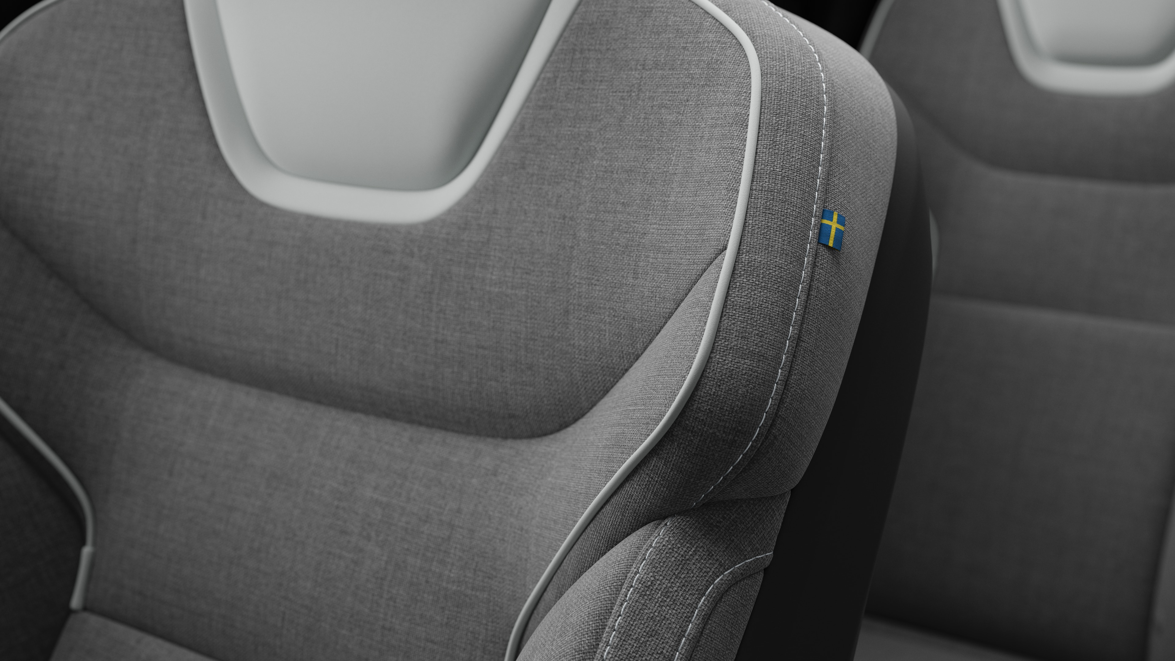 Close-up van het detail van het interieur van een Volvo-autostoel met stiksels en een klein Zweeds vlaglabel.
