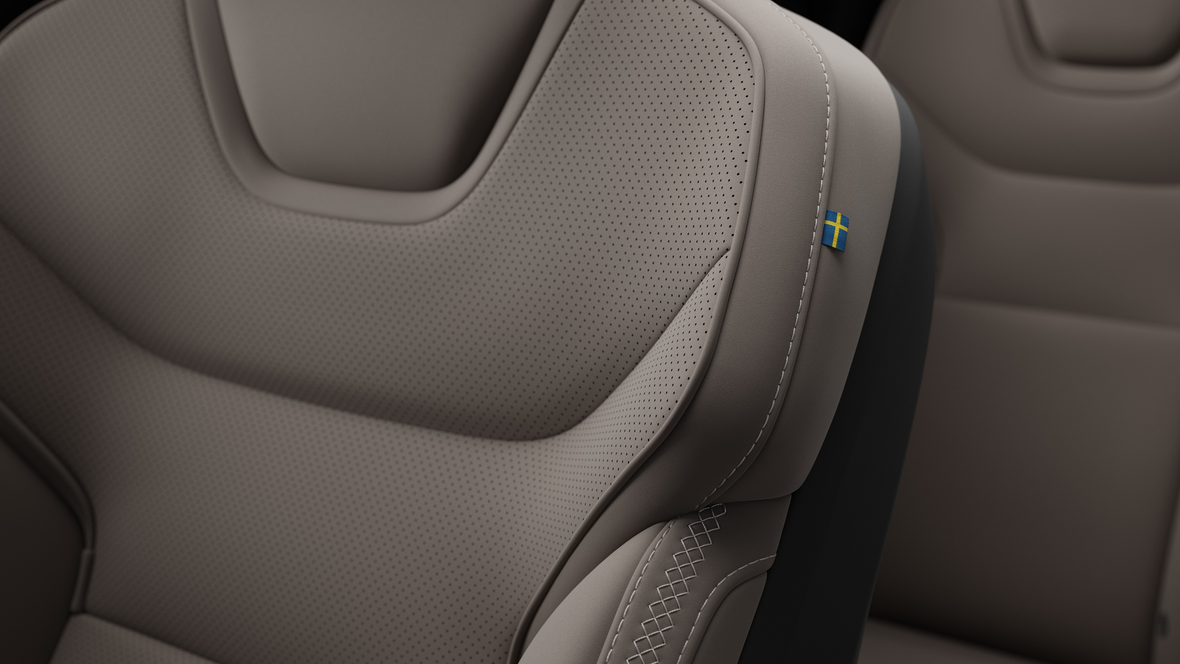 Close-up van het detail van het interieur van een Volvo-autostoel met stiksels en een klein Zweeds vlaglabel.