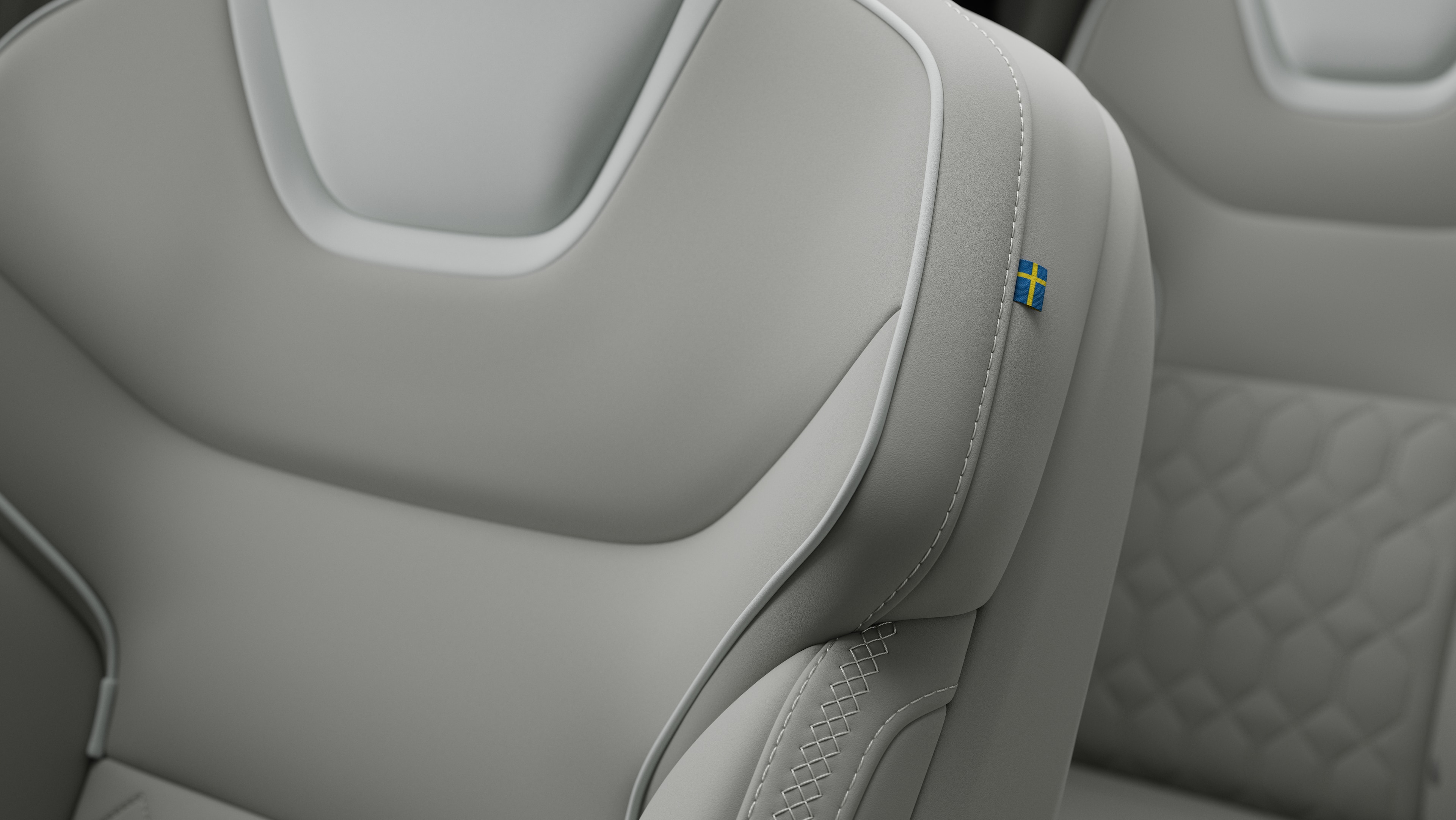 Close-up van het detail van het interieur van een Volvo-autostoel met stiksels en een klein Zweeds vlaglabel.