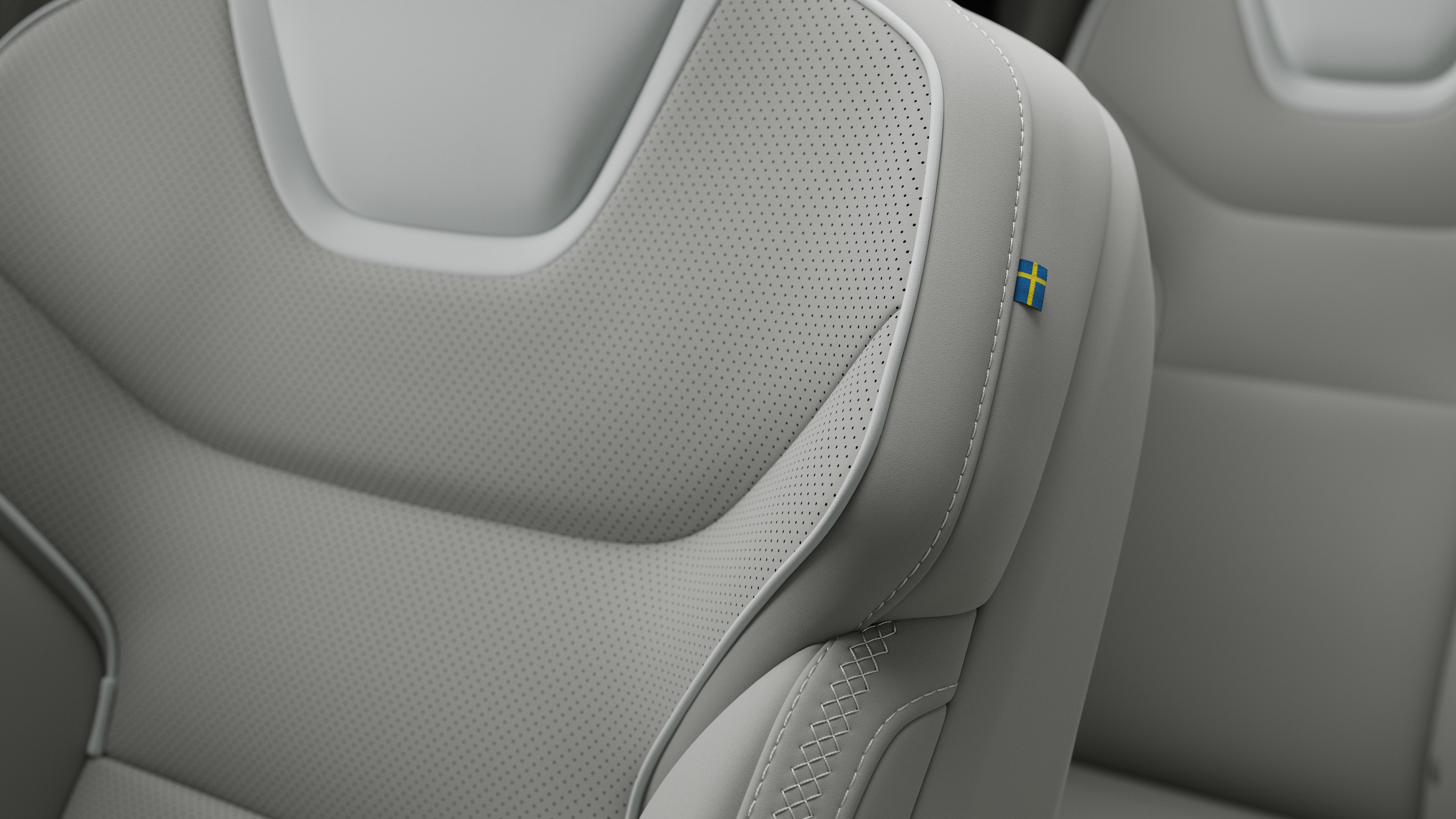 Close-up van het detail van het interieur van een Volvo-autostoel met stiksels en een klein Zweeds vlaglabel.