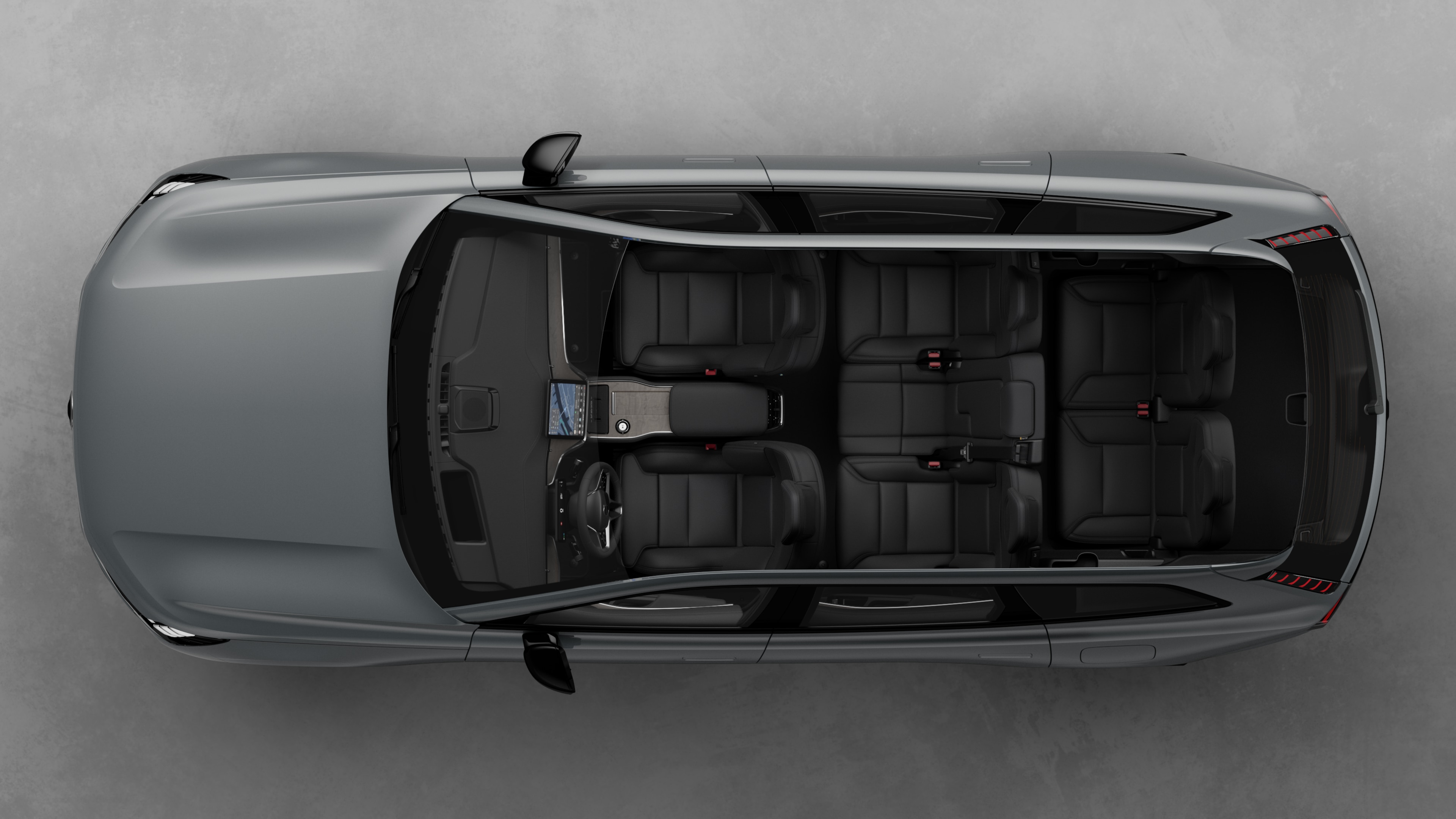 Top view of Volvo car interior, showing two rows of seats, dashboard, and center console, set against a plain studio background.