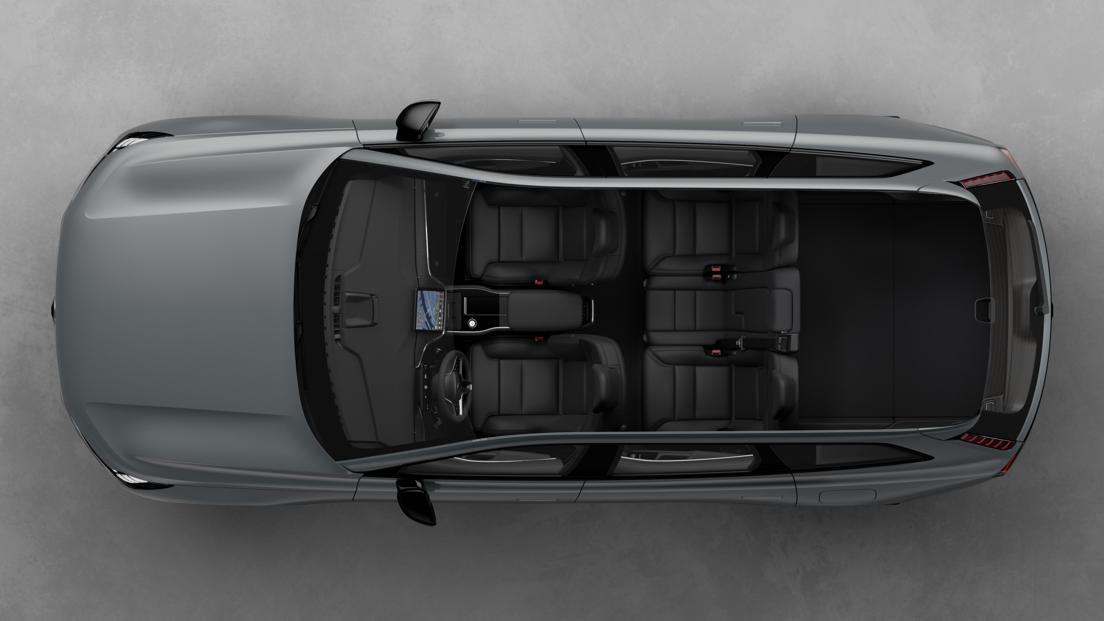 Widok z góry na wnętrze samochodu Volvo, przedstawiające dwa rzędy siedzeń, deskę rozdzielczą i konsolę środkową na tle zwykłego studia.