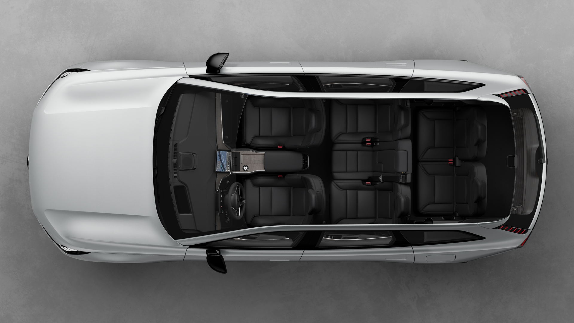 Vue de dessus de l’intérieur d’une Volvo, montrant deux rangées de sièges, le tableau de bord et la console centrale, sur un fond de studio uni.