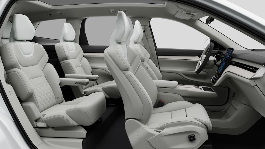 Volvo car interior side view showcasing front seats, rear passenger seats, steering wheel, dashboard, and center console, set against plain studio background.