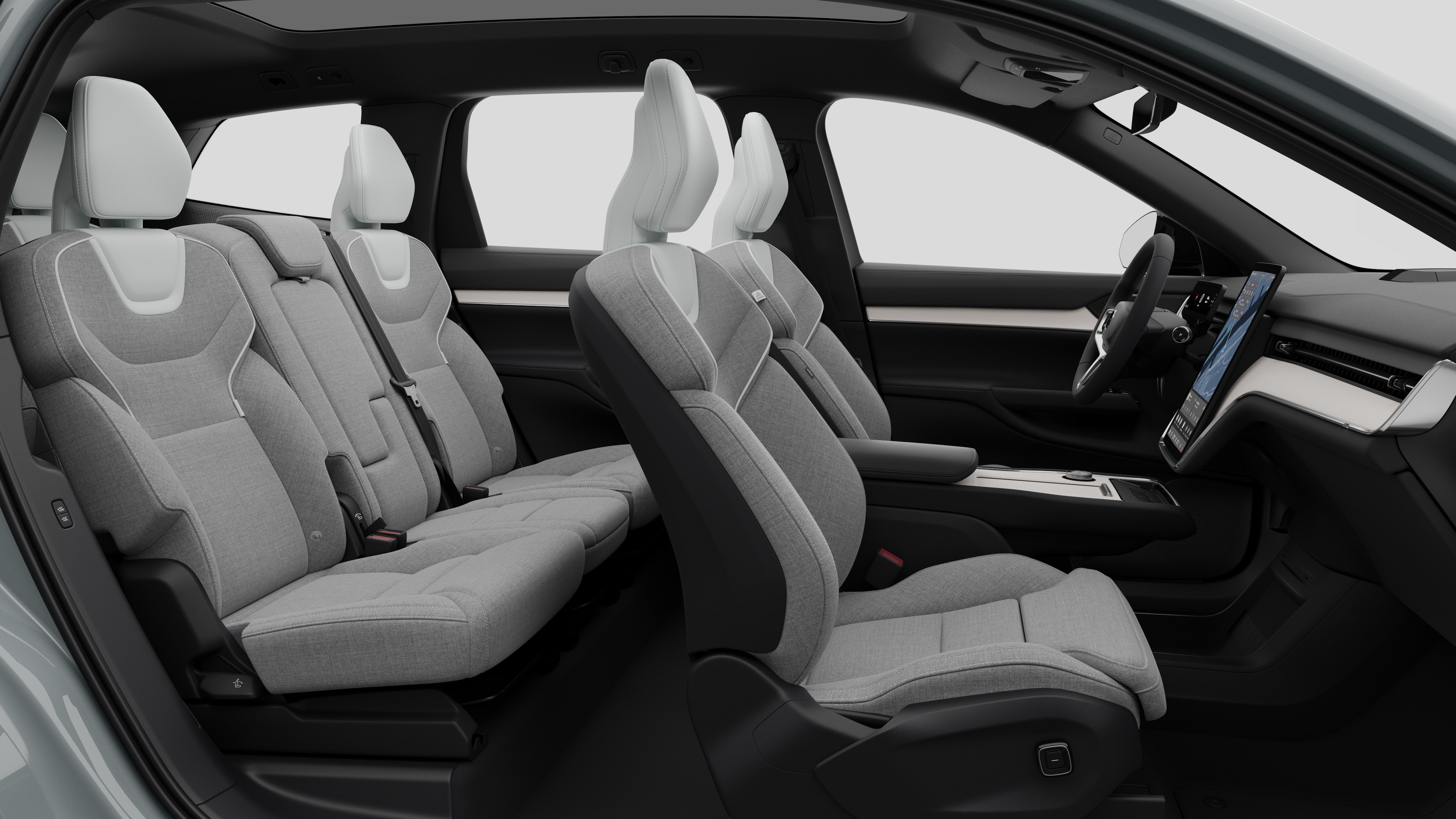 Zijaanzicht van het interieur van een Volvo met de voorstoelen, de passagiersstoelen achterin, het stuur, het dashboard en de middenconsole, tegen een effen studioachtergrond.