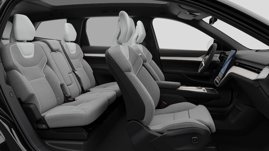 Vue latérale de l’intérieur d’une Volvo montrant les sièges avant, les sièges passager arrière, le volant, le tableau de bord et la console centrale, sur fond de studio.