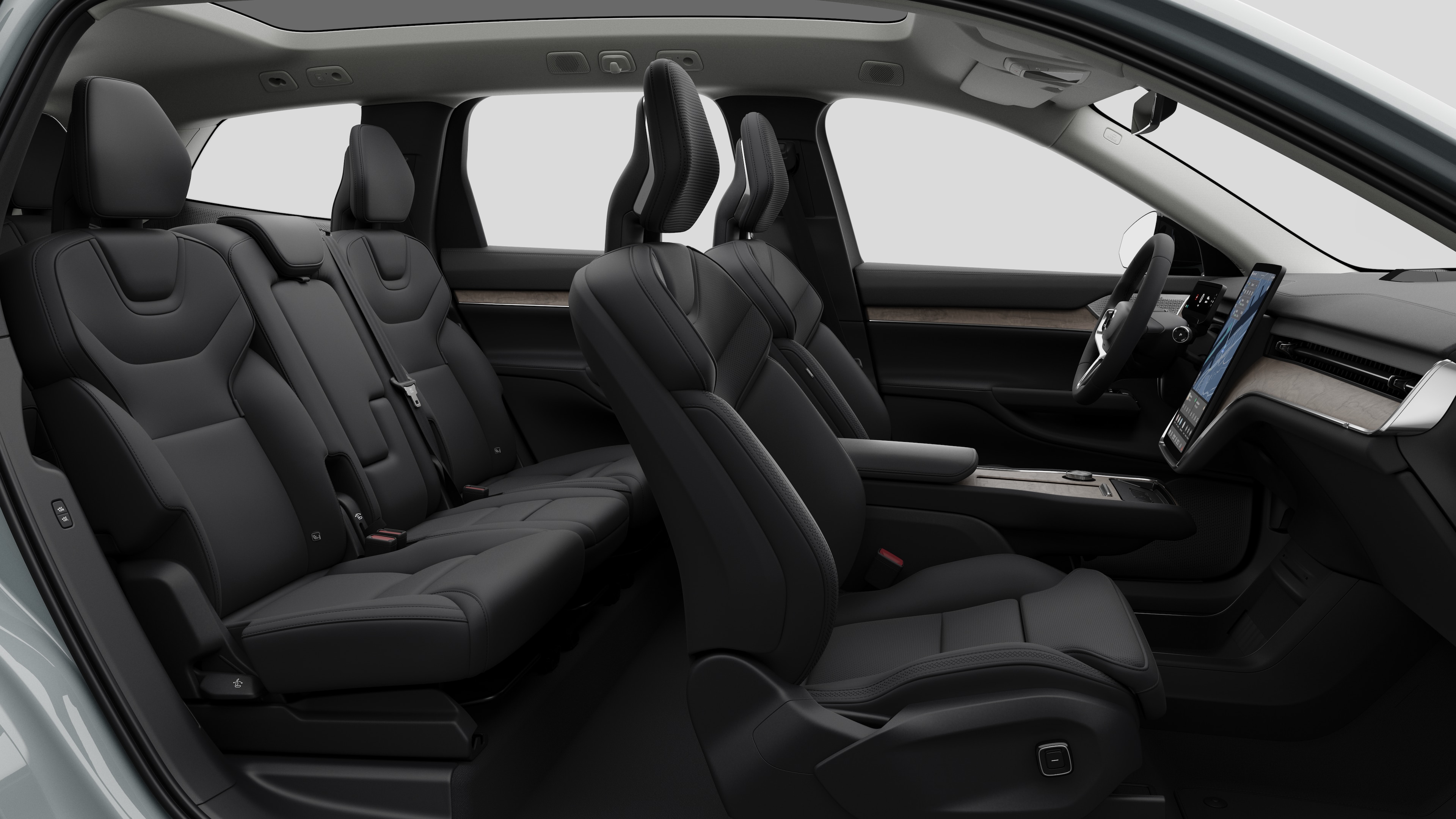 Vista lateral do interior do carro Volvo mostrando os bancos dianteiros, traseiros do passageiro, volante, painel de instrumentos e console central, contra um plano de fundo de estúdio simples.