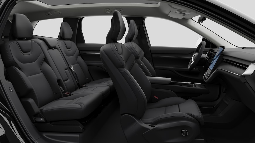 Seitenansicht des Innenraums eines Volvo mit Vordersitzen, Beifahrersitzen, Lenkrad, Armaturenbrett und Mittelkonsole vor einem schlichten Studiohintergrund.