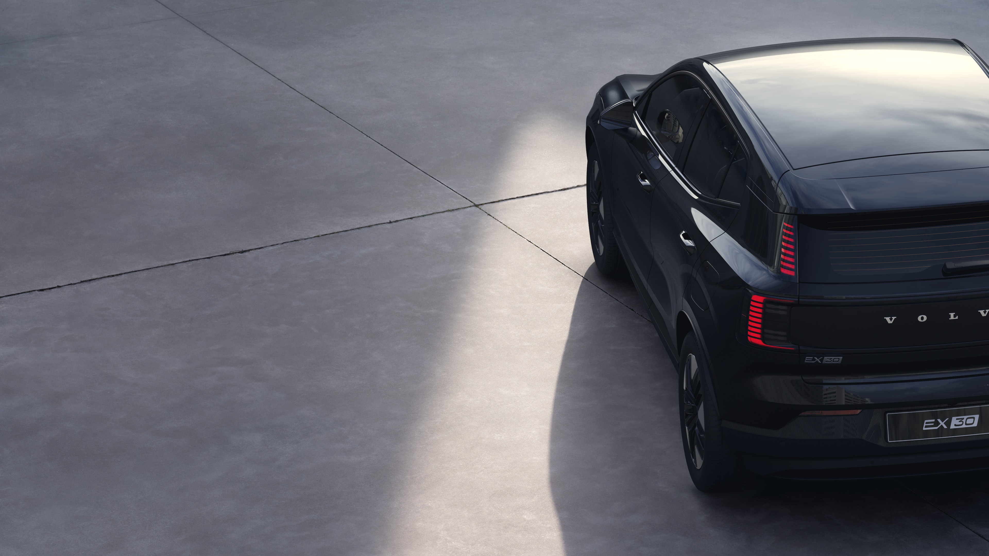 Vista traseira de três quartos do carro Volvo em fundo de estúdio simples, apresentando o design da lanterna traseira e a estrutura do vidro traseiro para detalhes externos.