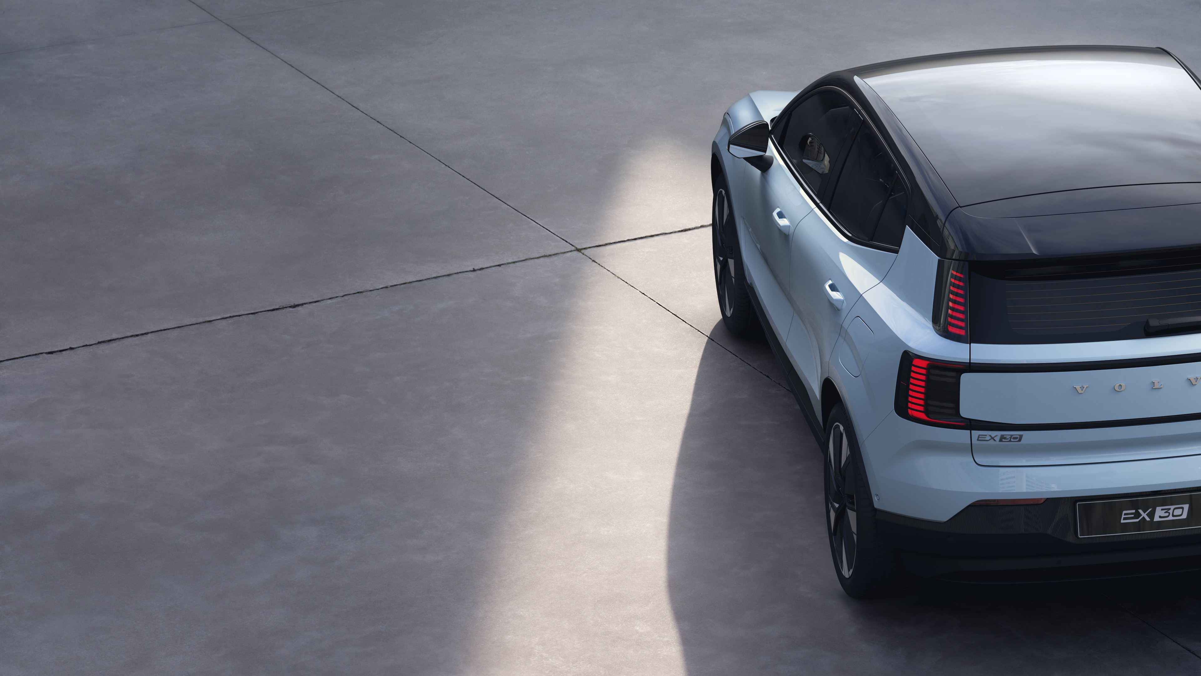 Vista traseira de três quartos do carro Volvo em fundo de estúdio simples, apresentando o design da lanterna traseira e a estrutura do vidro traseiro para detalhes externos.