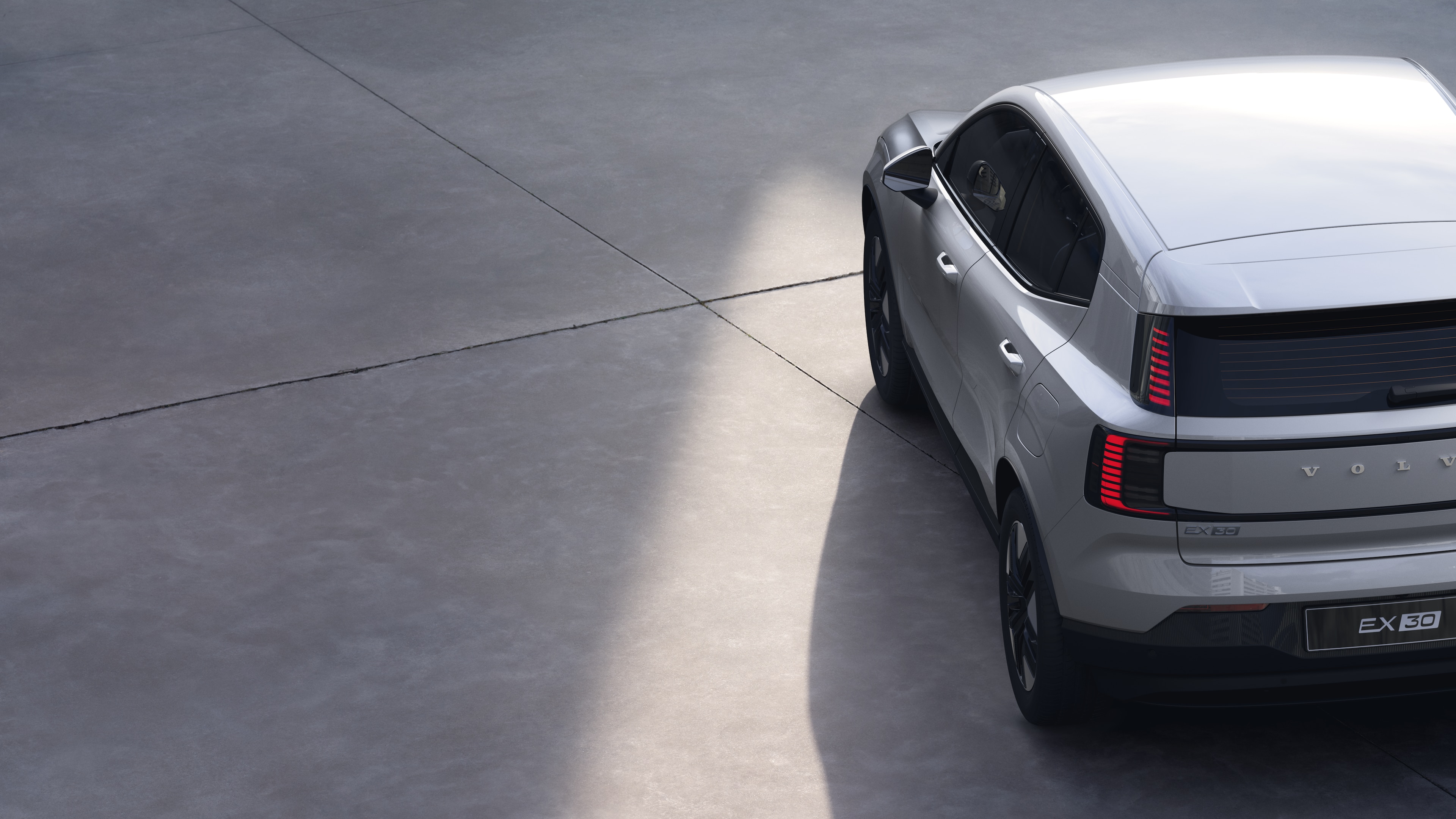 Vista traseira de três quartos do carro Volvo em fundo de estúdio simples, apresentando o design da lanterna traseira e a estrutura do vidro traseiro para detalhes externos.