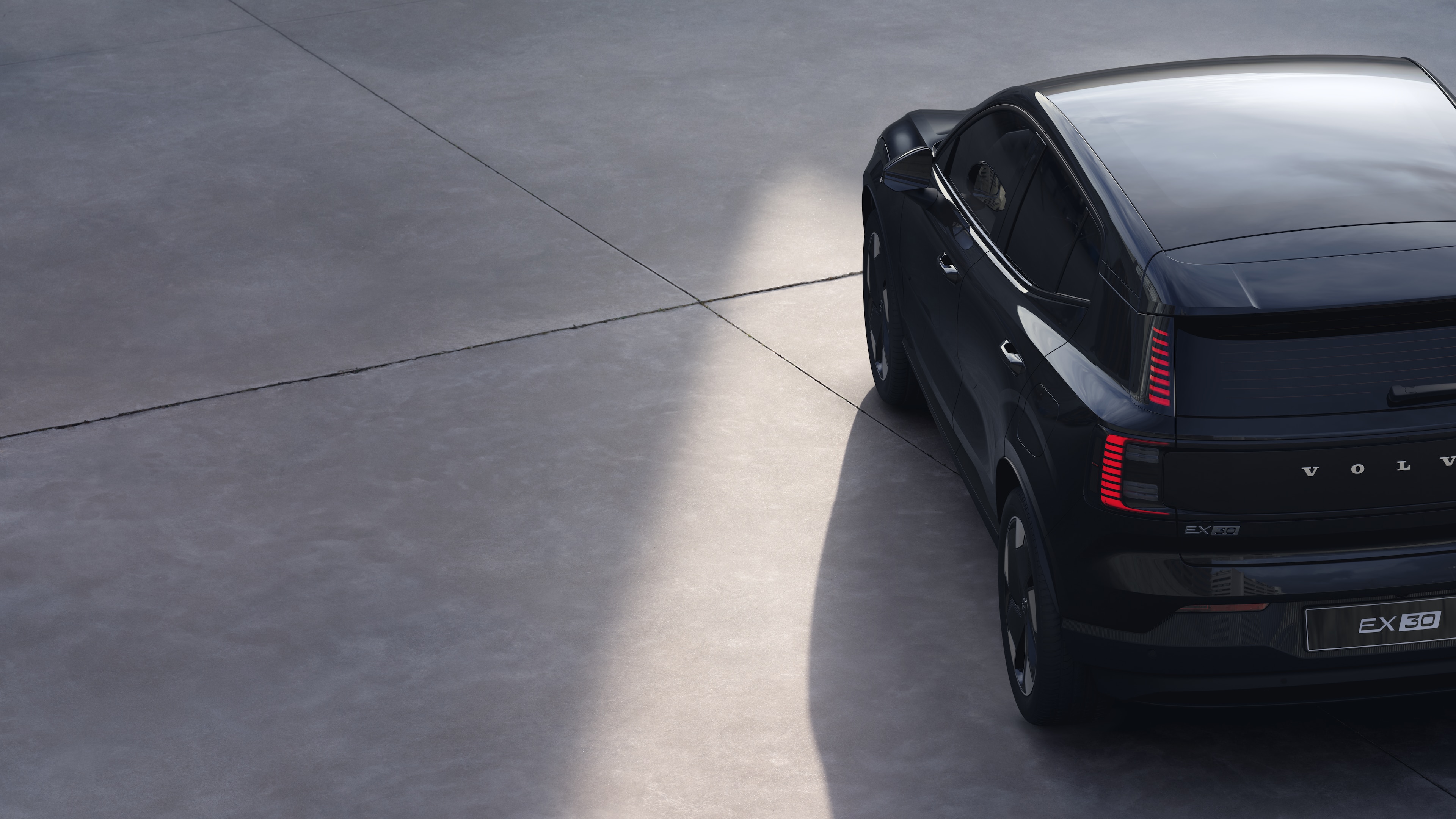 Volvo car three-quarter rear view on plain studio background, showcasing taillight design and rear window structure for exterior detailing.