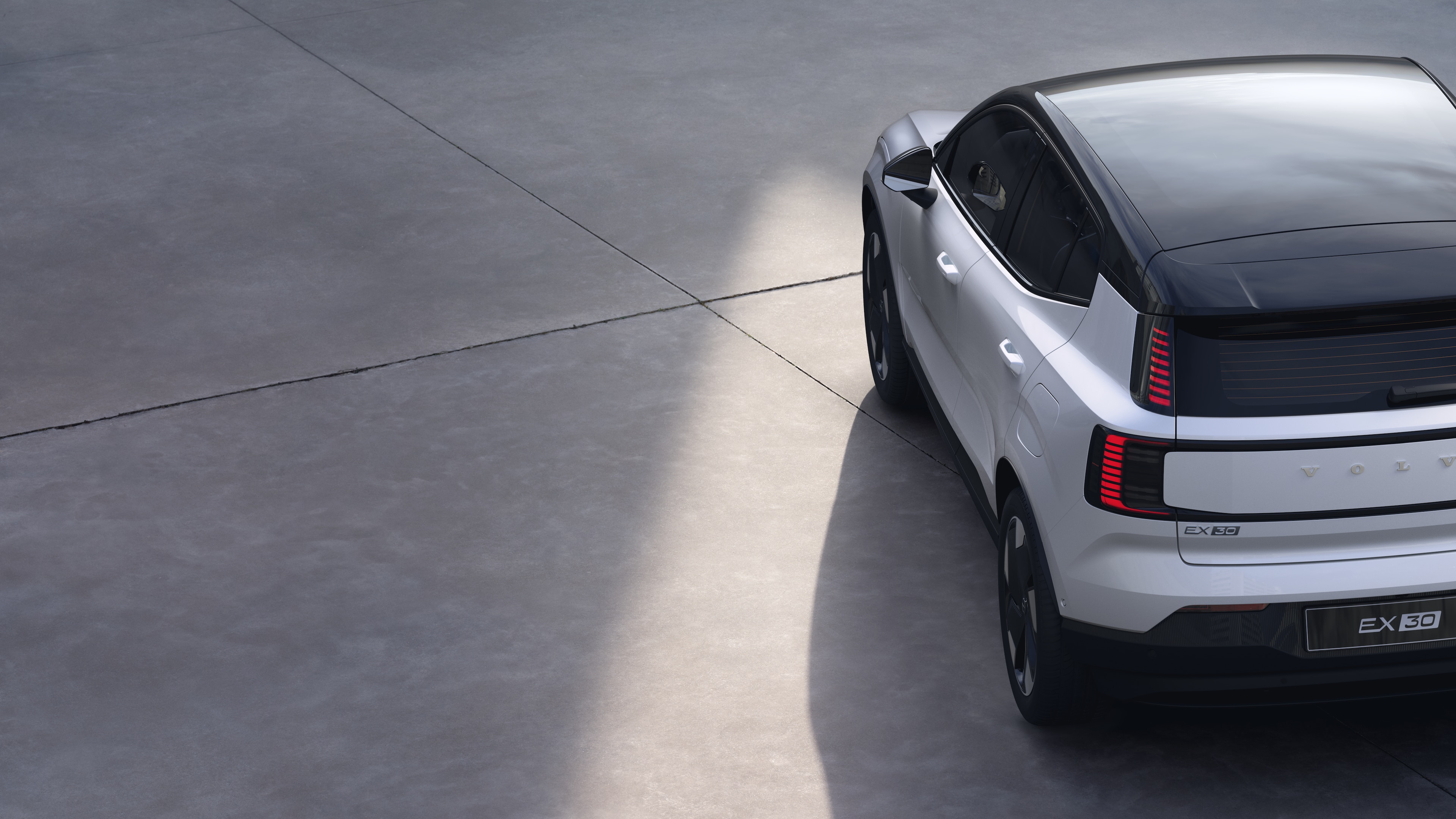 Volvo car three-quarter rear view on plain studio background, showcasing taillight design and rear window structure for exterior detailing.