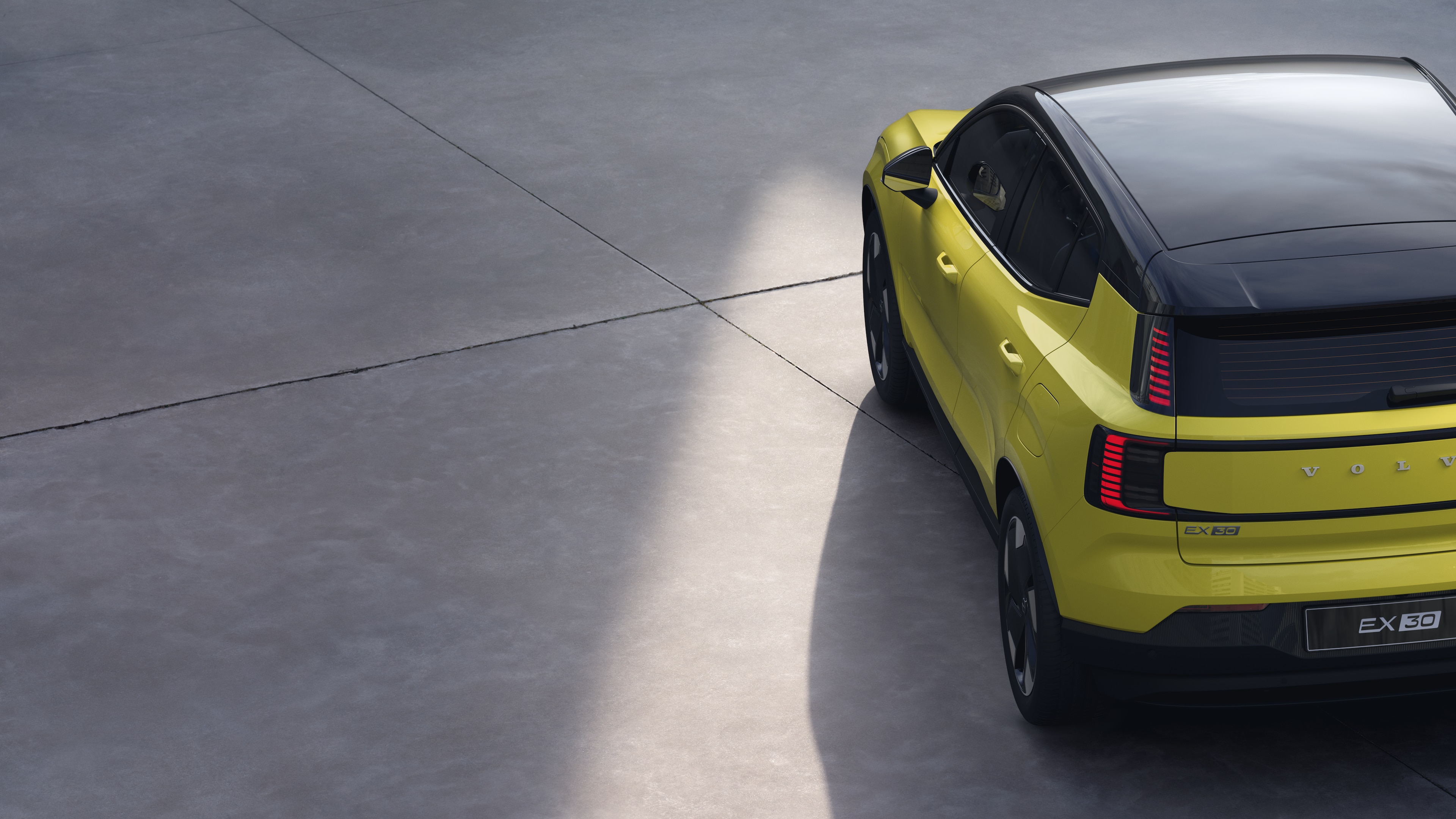 Volvo car three-quarter rear view on plain studio background, showcasing taillight design and rear window structure for exterior detailing.