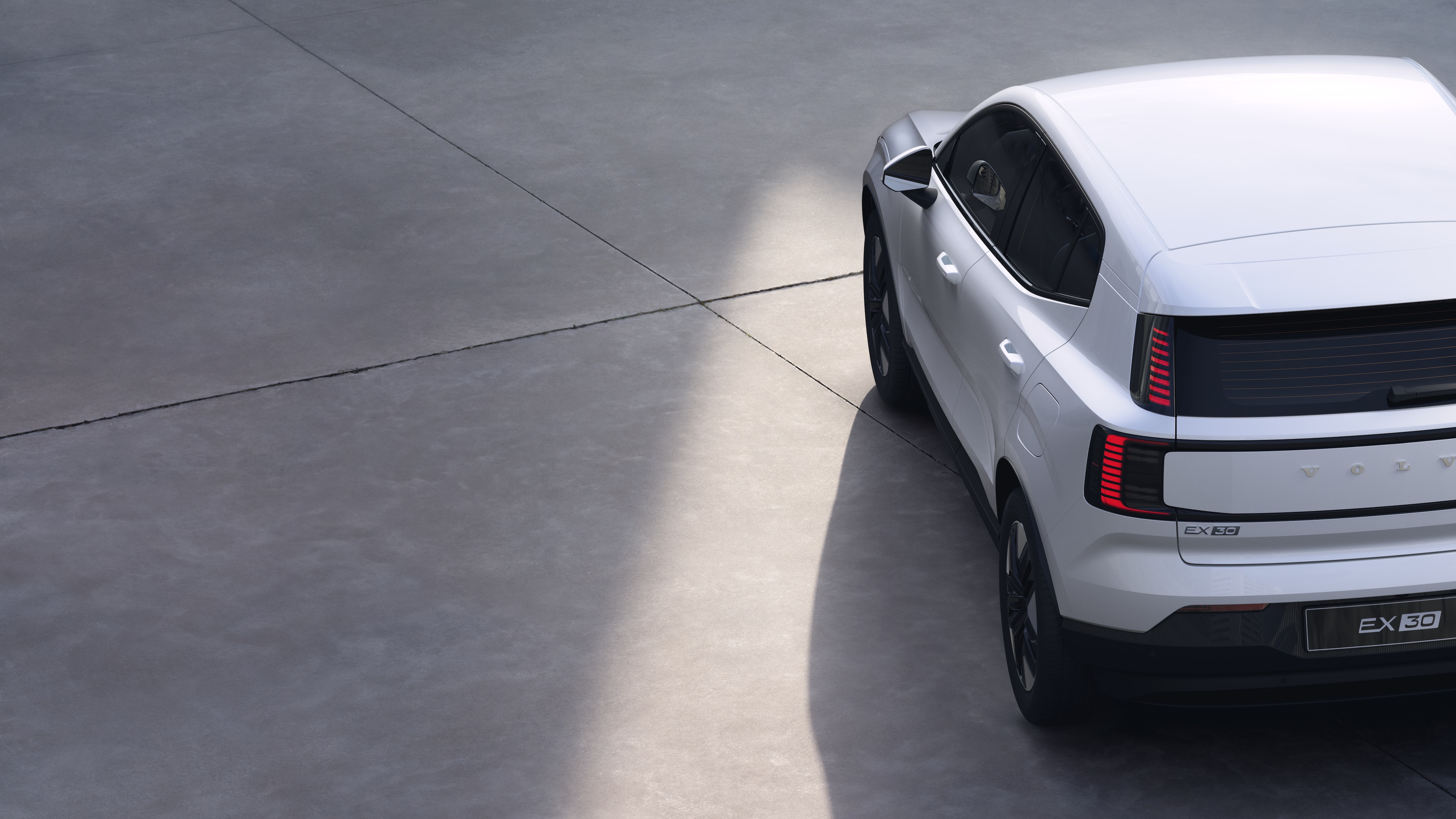 Volvo car three-quarter rear view on plain studio background, showcasing taillight design and rear window structure for exterior detailing.