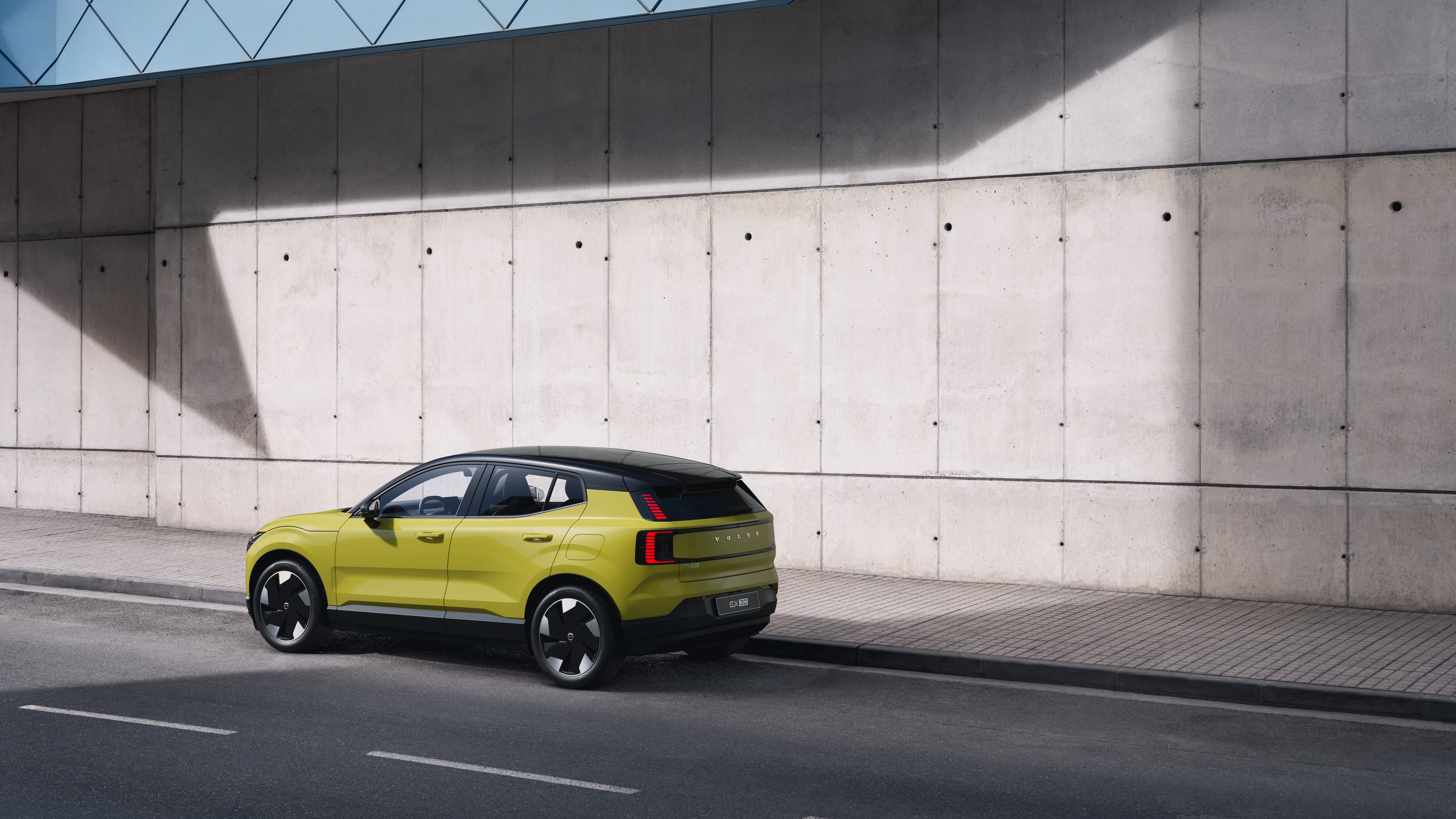 Carro Volvo na traseira estacionado contra uma parede de concreto em um fundo de rua urbana.