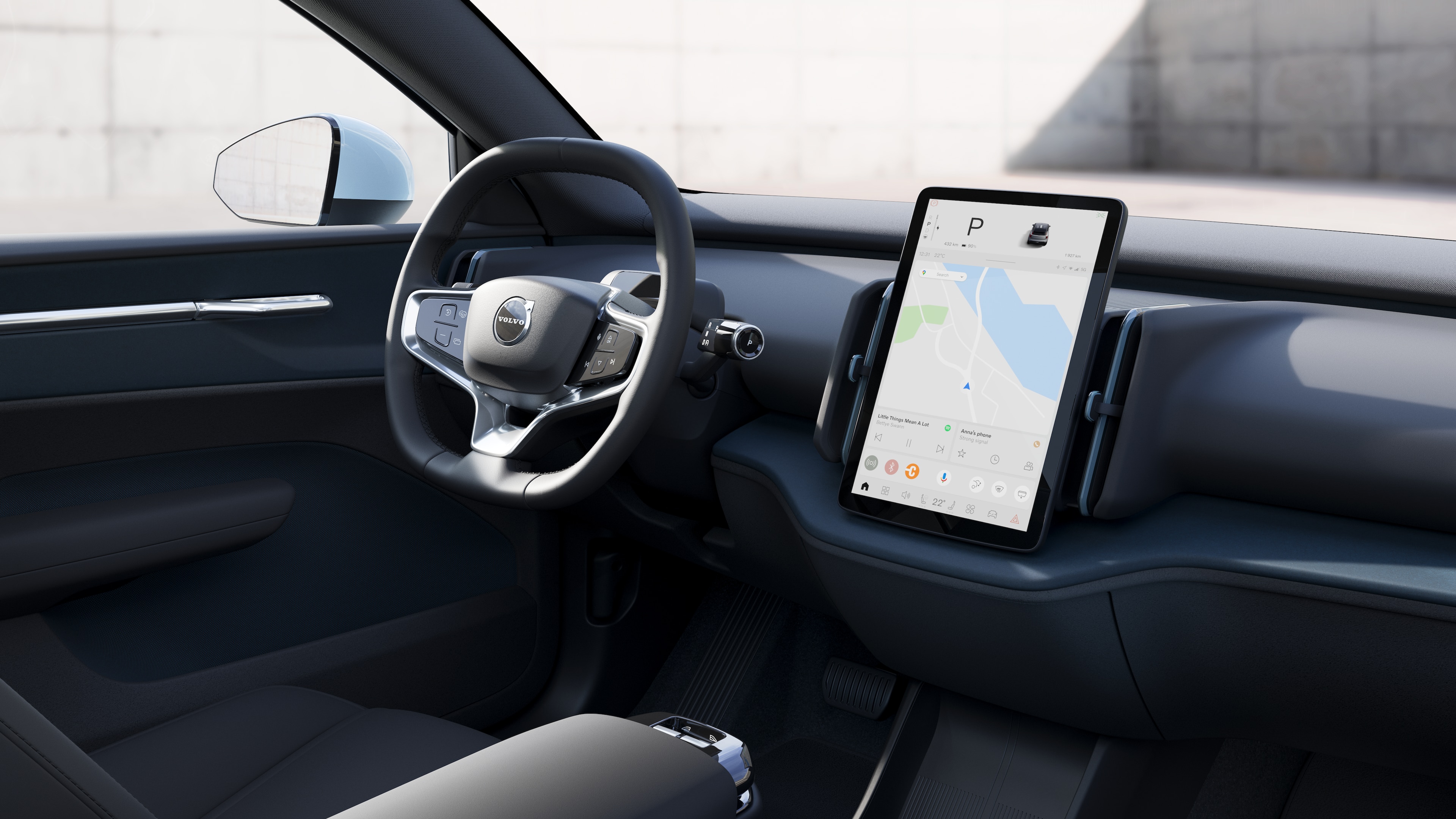 Interno di un'auto Volvo che mostra cruscotto, volante e console centrale con display digitale sullo sfondo di una strada aperta.