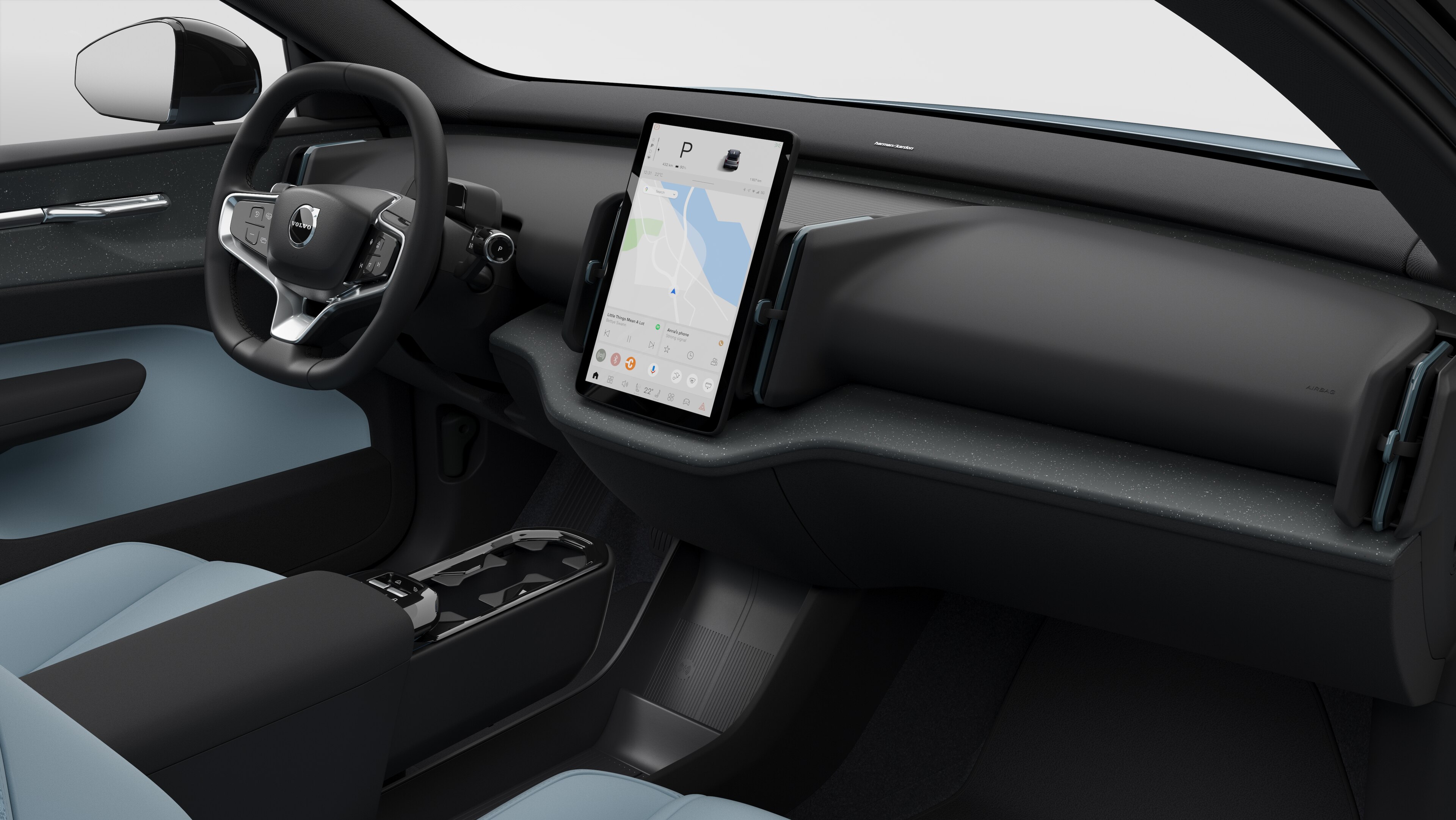 Interior view of a Volvo car showing the dashboard, steering wheel, center console, and digital display screen in a plain studio background.