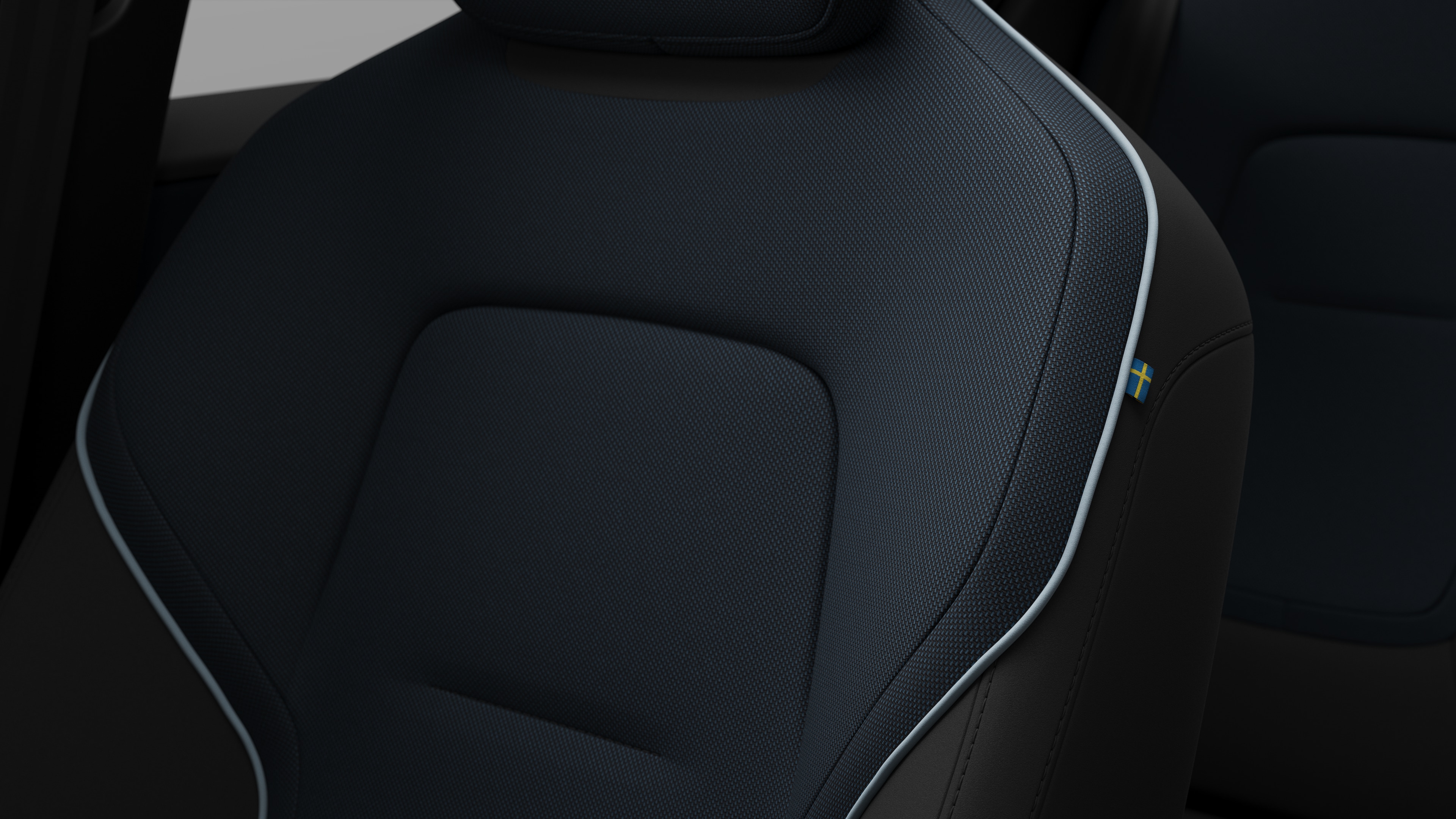 Primer plano del detalle del asiento interior del vehículo Volvo que muestra costuras y una pequeña etiqueta con la bandera sueca.
